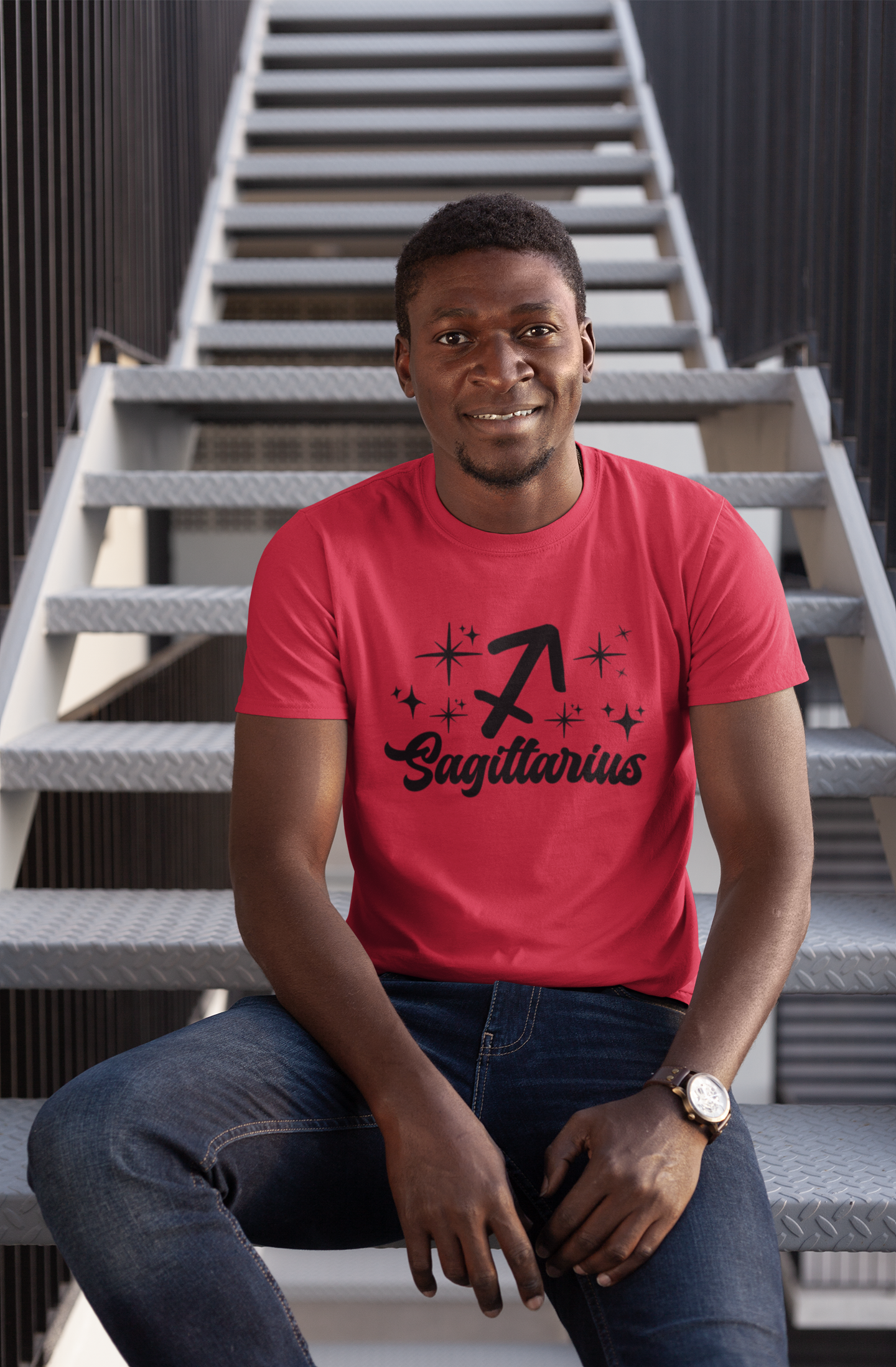 Man wearing a red t-shirt with 'Sagittarius' black text design sitting on stairs.