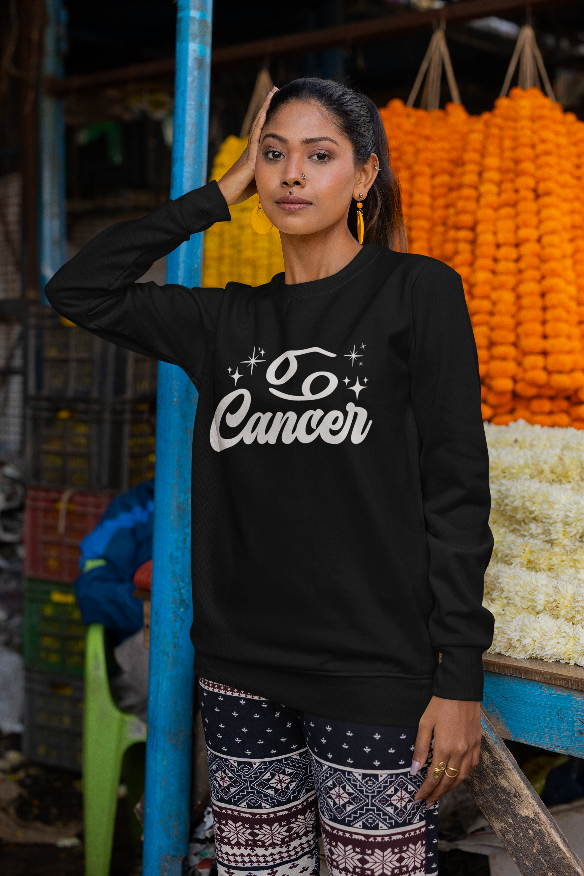 Woman wearing a black sweatshirt with 'Cancer' white text in an outdoor market setting