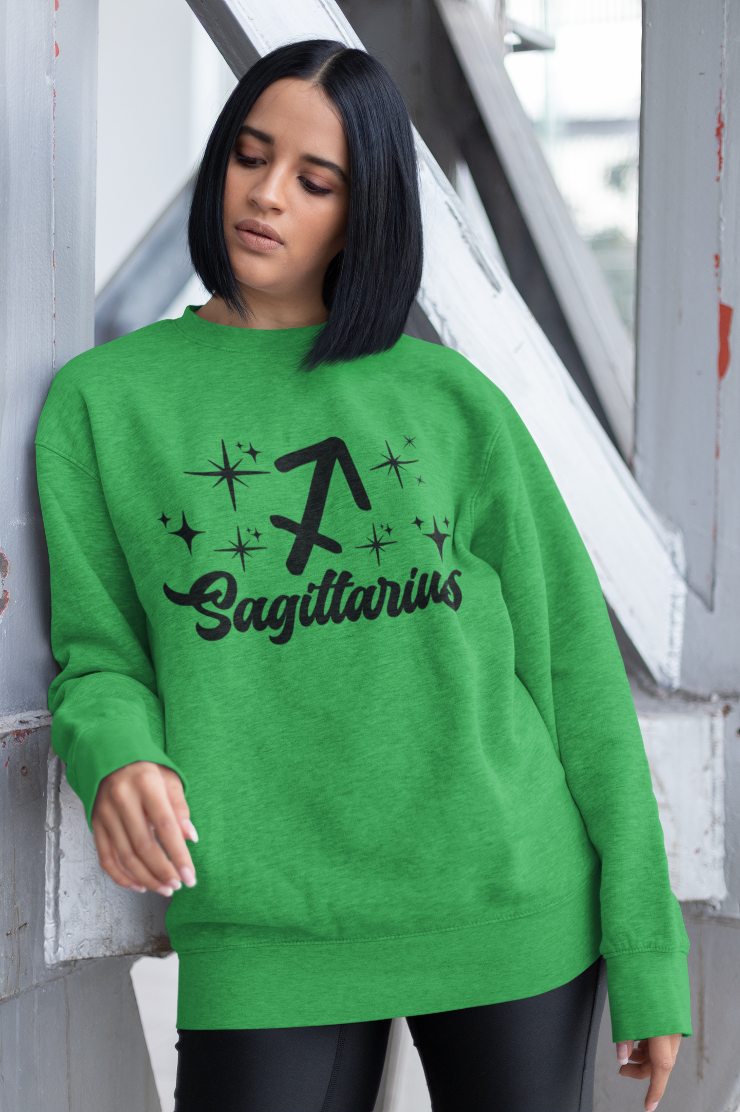 Person wearing a green sweatshirt with 'Sagittarius' black text design outdoors.