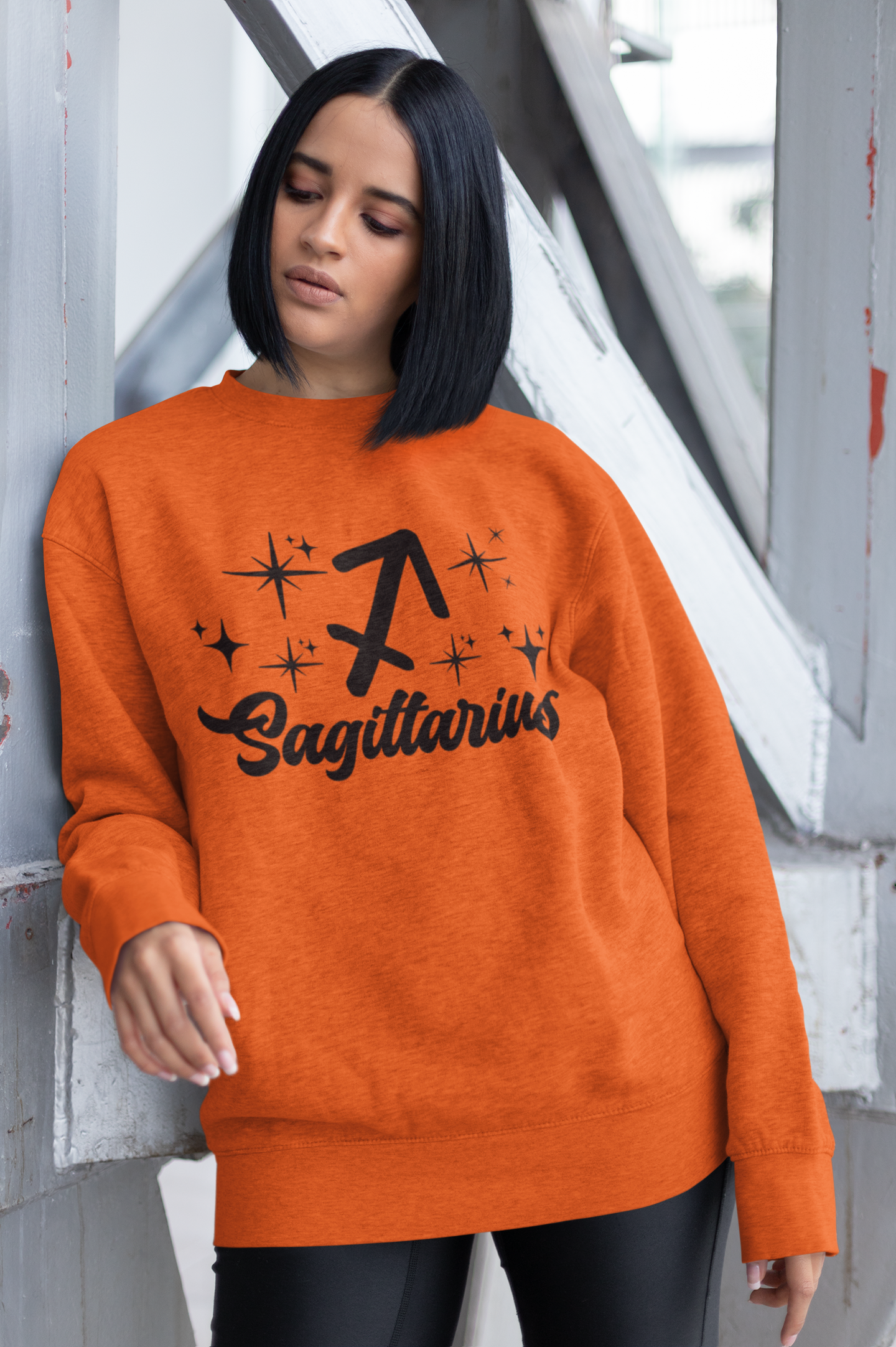 Person wearing a orange sweatshirt with 'Sagittarius' black text design outdoors.