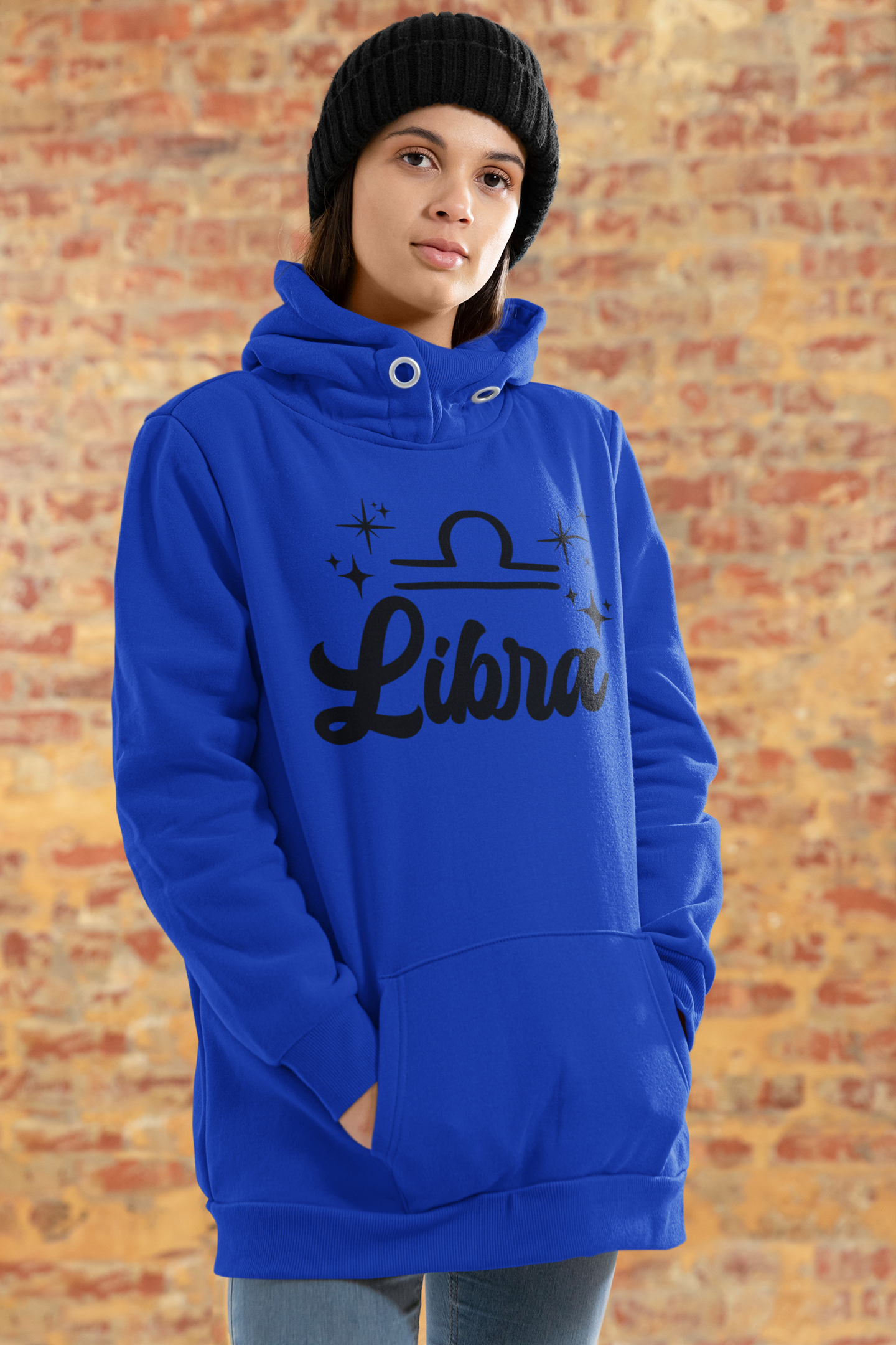 Person wearing a blue hoodie with 'Libra' black text design standing in front of a brick wall