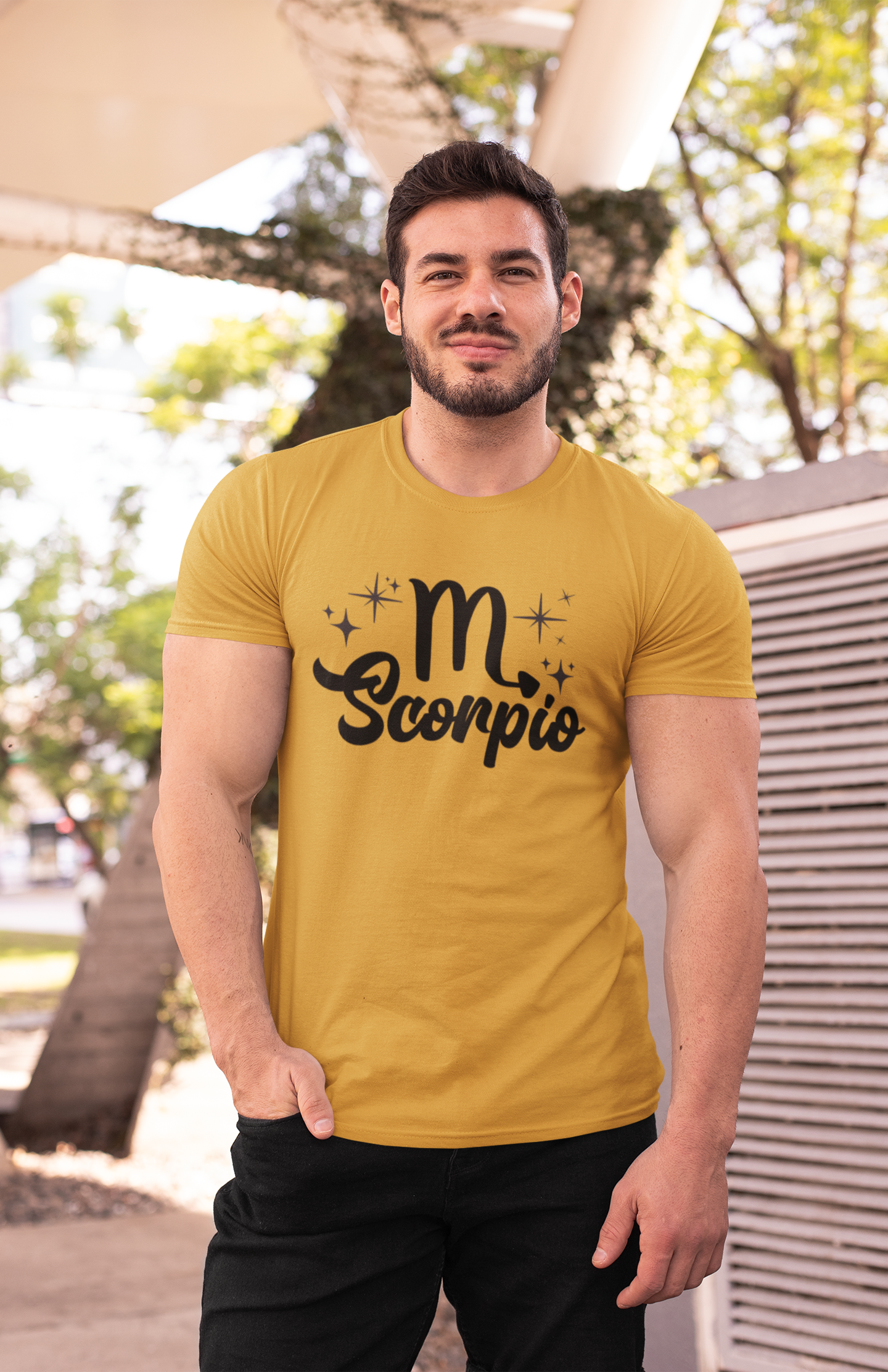 Man wearing an gold t-shirt with 'Scorpio' black text design outdoors.