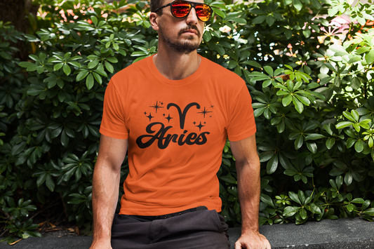 Man wearing an orange t-shirt with 'Aries' black text design sitting outdoors.