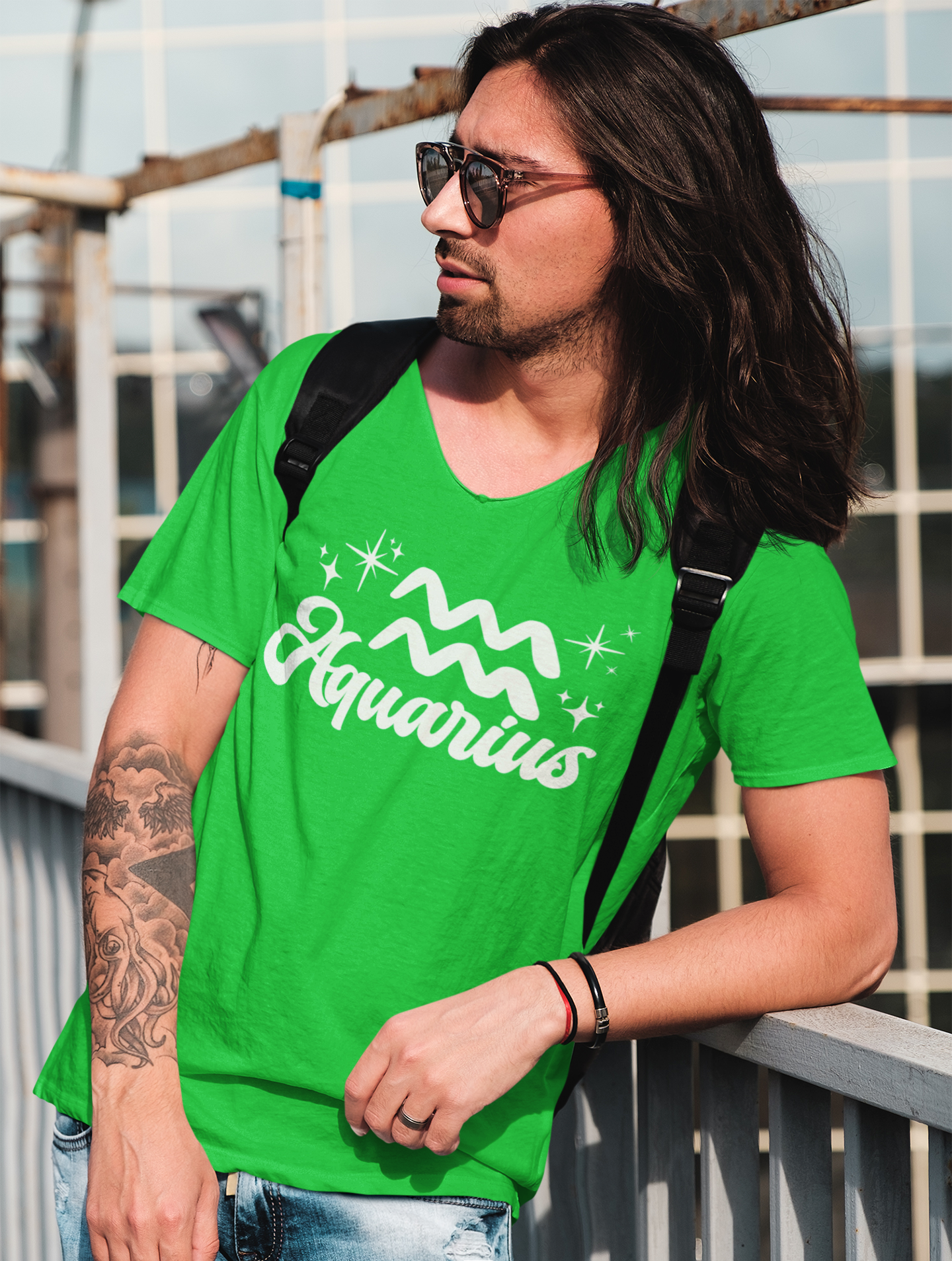 Person wearing a green 'Aquarius' t-shirt - white text design, with sunglasses and a backpack.