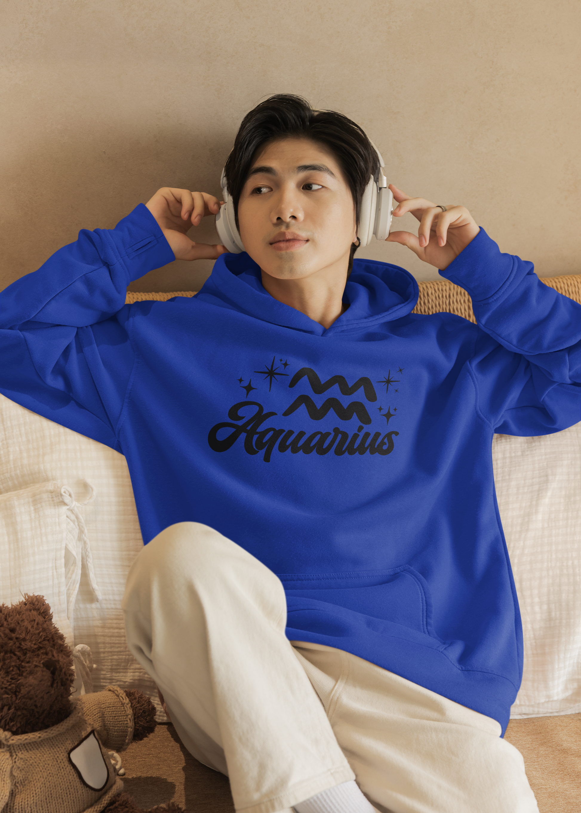 Person wearing a blue hoodie with 'Aquarius' black text with zodiac symbol, sitting on a couch.