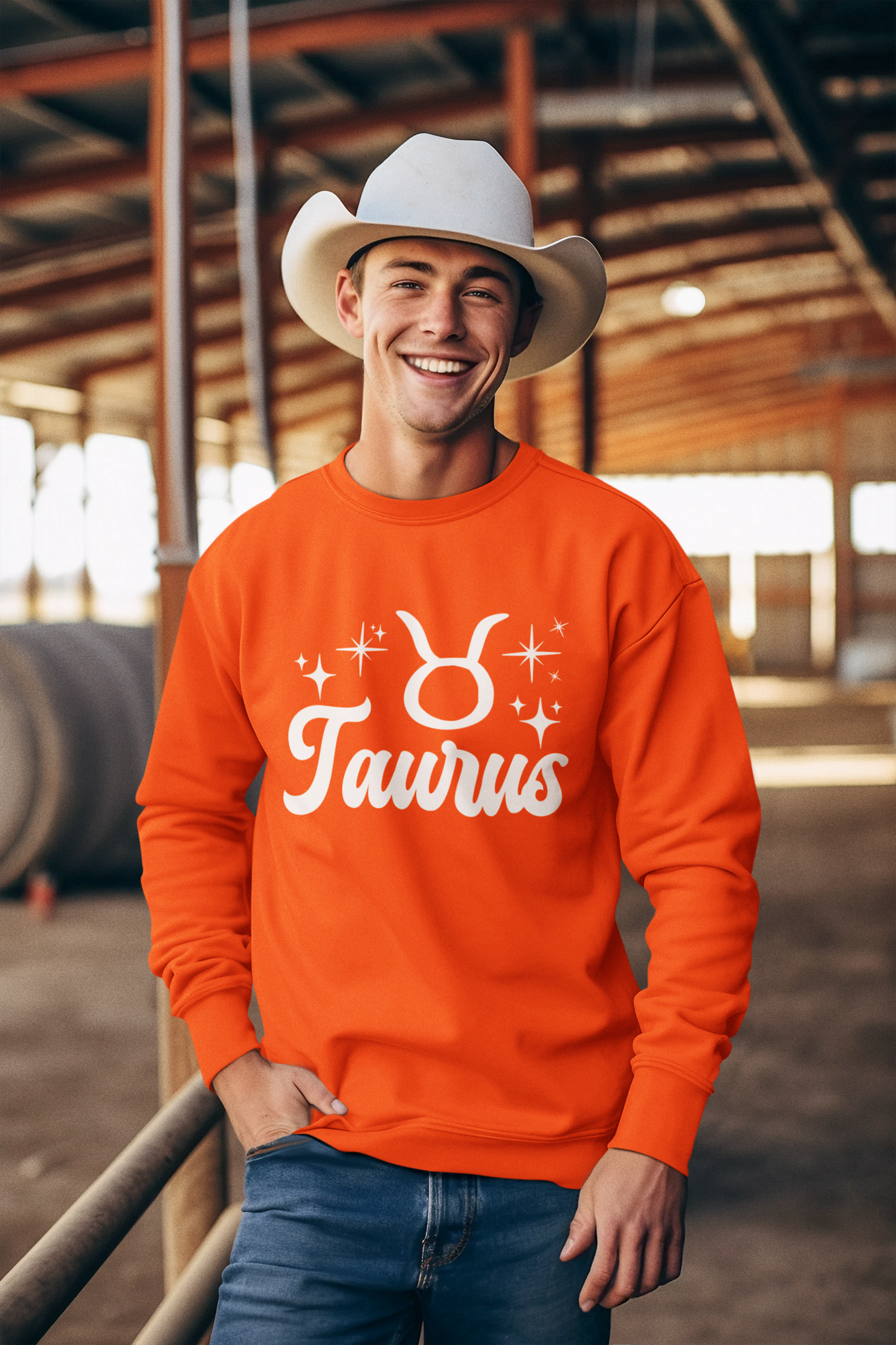 Man wearing a orange 'Taurus' white text design sweatshirt in an barn setting