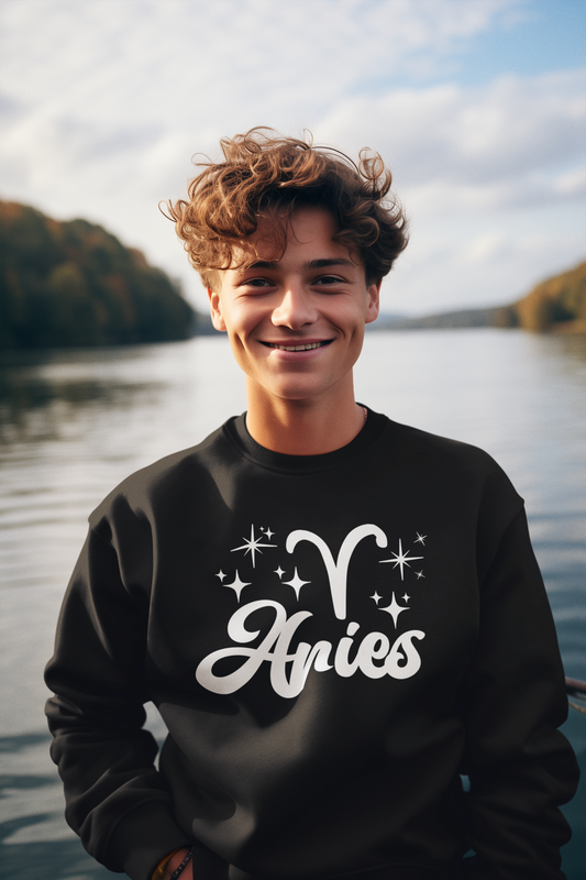 Person wearing a black sweatshirt with 'Aries' white text design by a lake