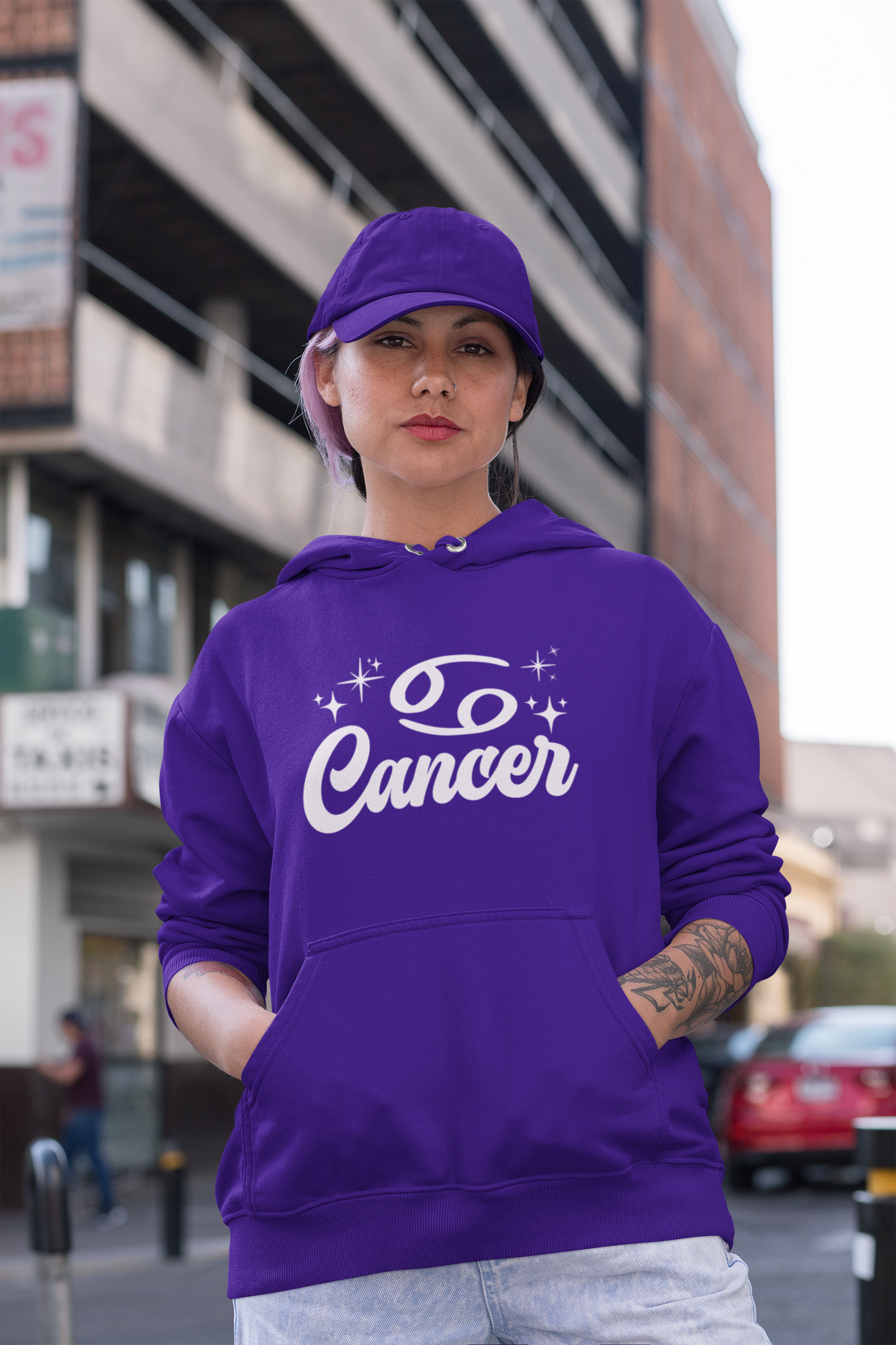 Person wearing a purple hoodie with 'Cancer' white text in an urban setting