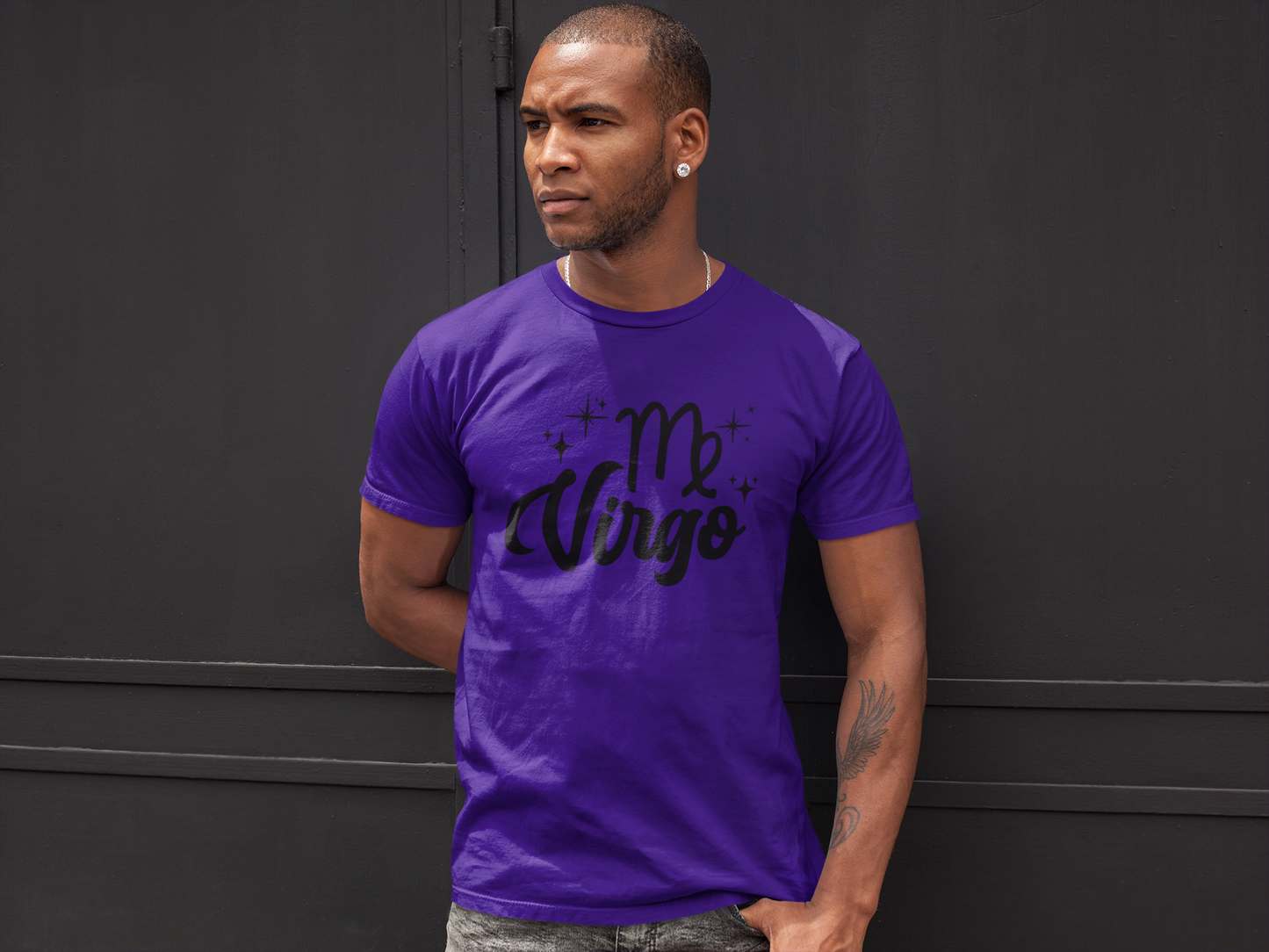 Man wearing a purple t-shirt with 'Virgo' black text against a black wall background