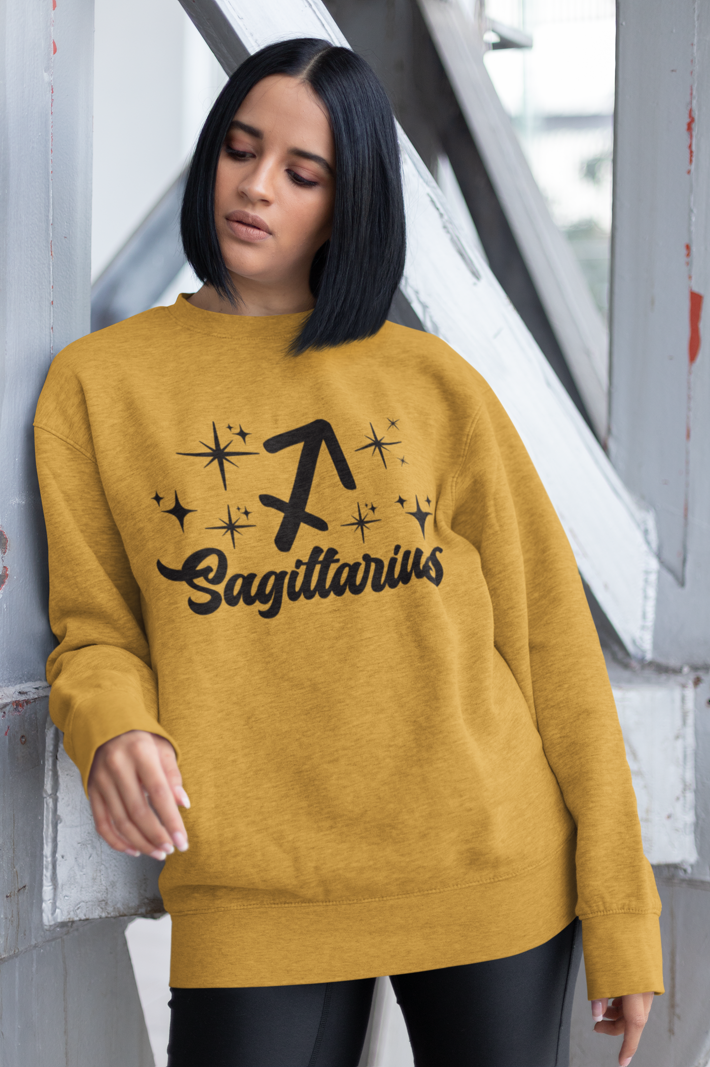 Person wearing a gold sweatshirt with 'Sagittarius' black text design outdoors.