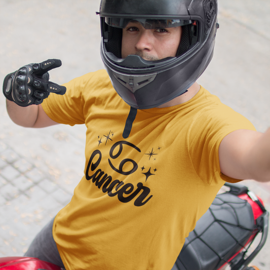 Person wearing a gold t-shirt with 'Leo Cancer' black text, black helmet, and gloves on a motorcycle.
