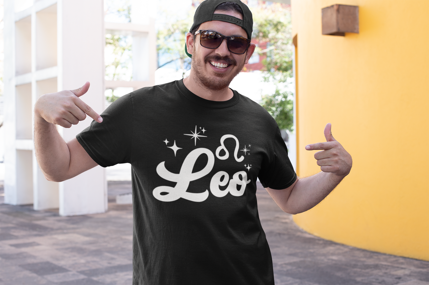Man wearing a black t-shirt with 'Leo' white text design, giving thumbs up outdoors.