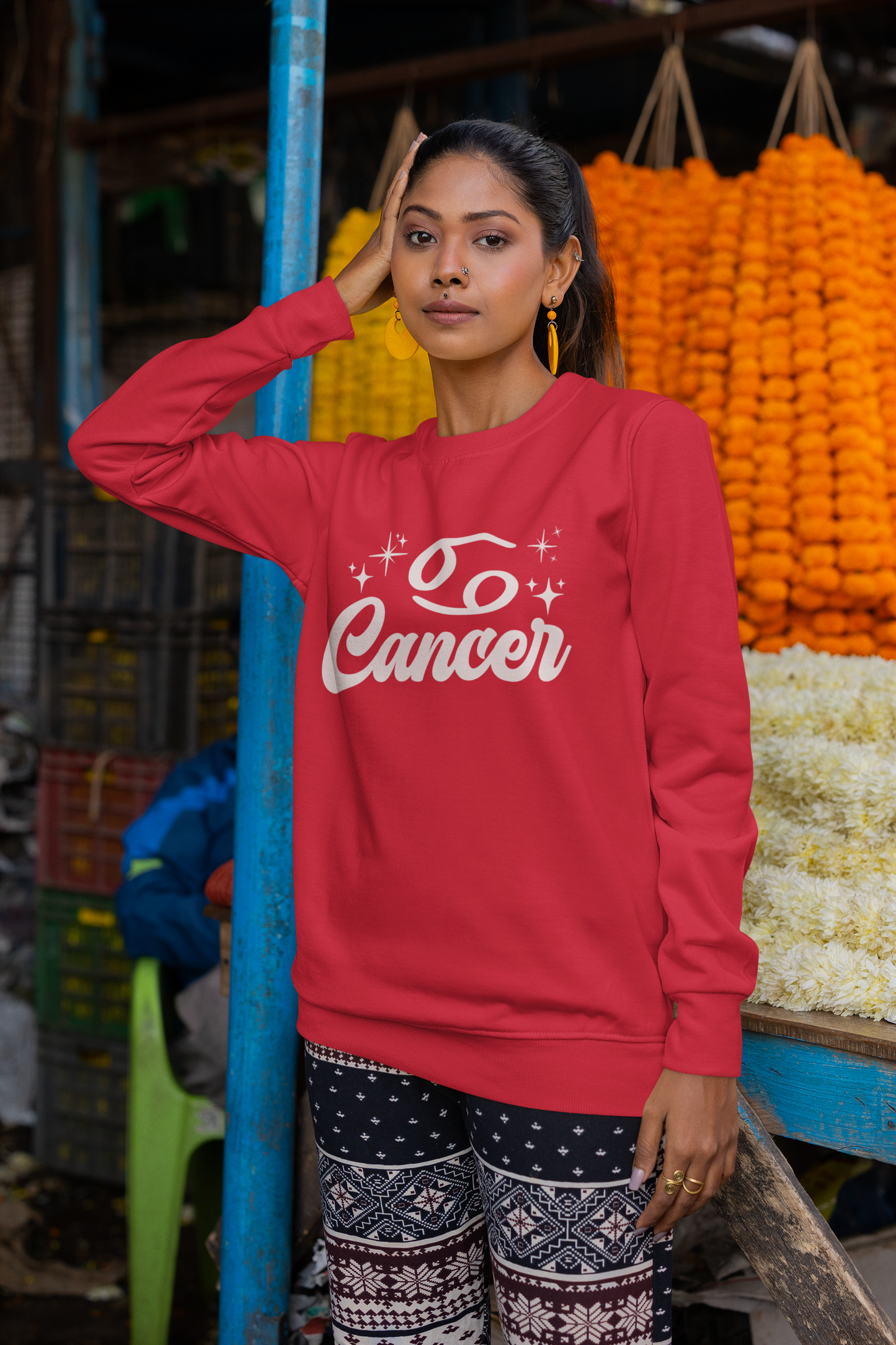 Woman wearing a red sweatshirt with 'Cancer' white text in an outdoor market setting