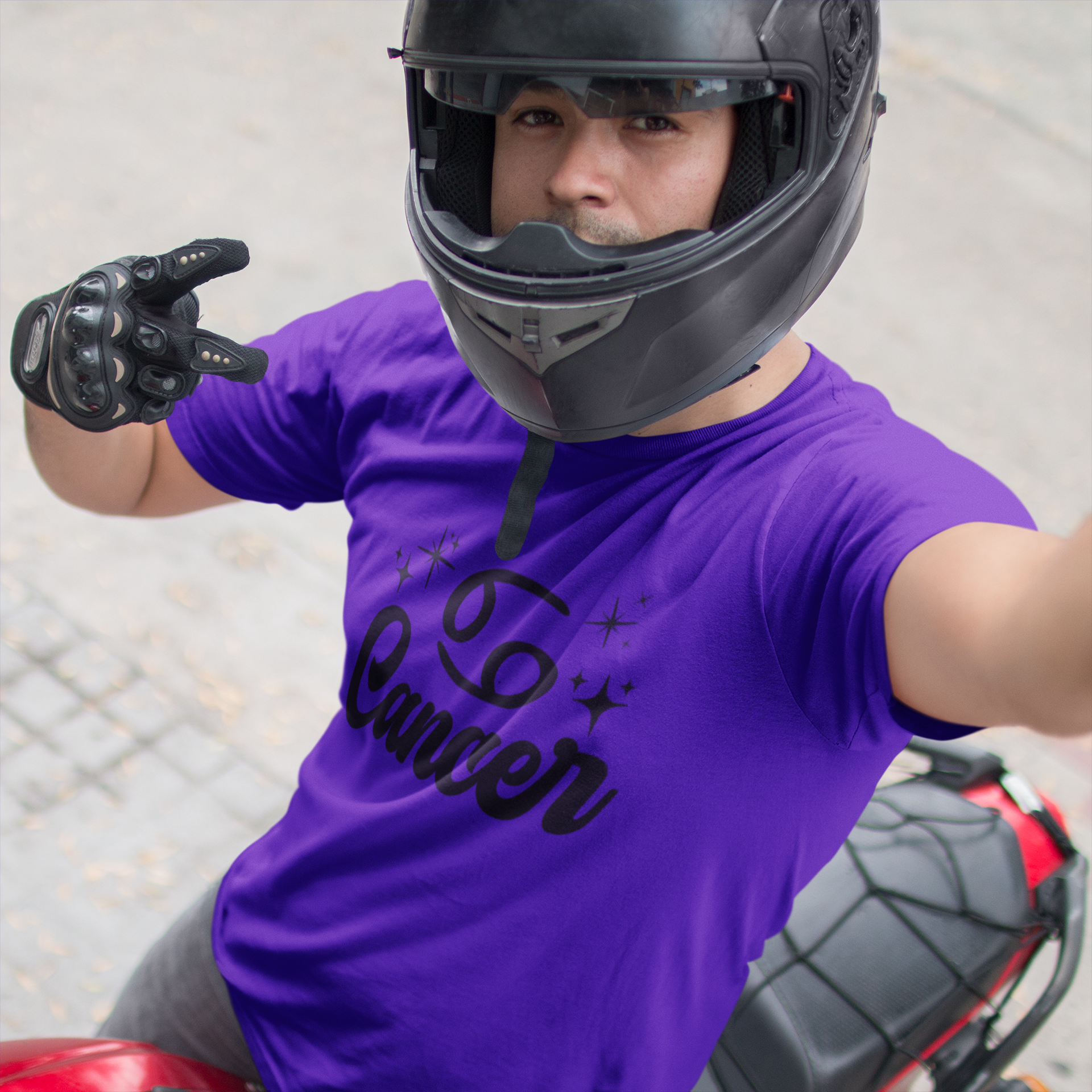 Person wearing a purple t-shirt with 'Leo Cancer' black text, black helmet, and gloves on a motorcycle.