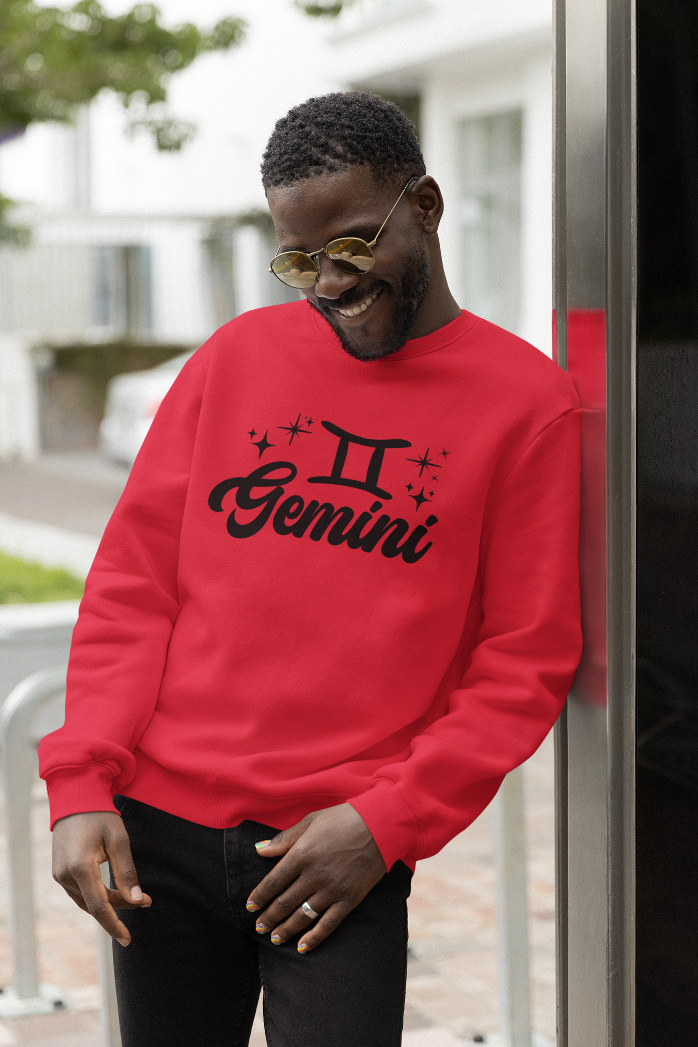 Person wearing a red 'Gemini' black text design sweatshirt with zodiac symbol outdoors.