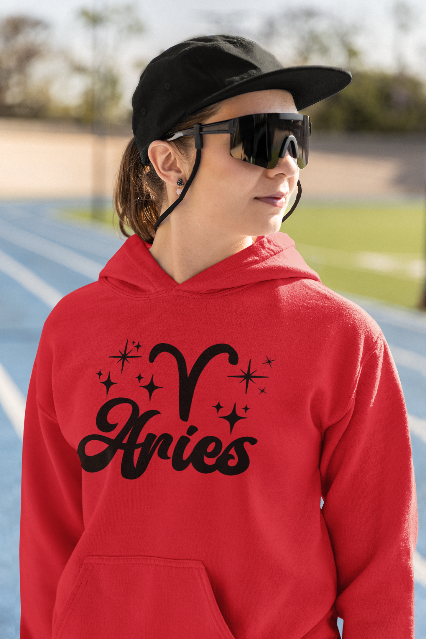 Person wearing a red hoodie with black 'Aries' text and zodiac symbol outdoors.