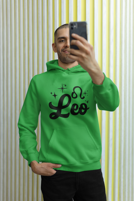 Person wearing a green hoodie with 'Leo' black text, taking a selfie against a striped wall.