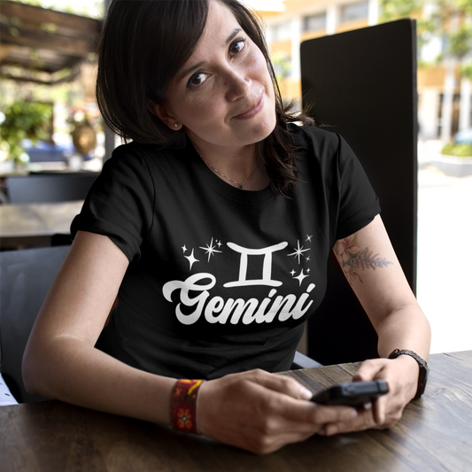Person wearing a black t-shirt with 'Gemini' white text design sitting at a table.