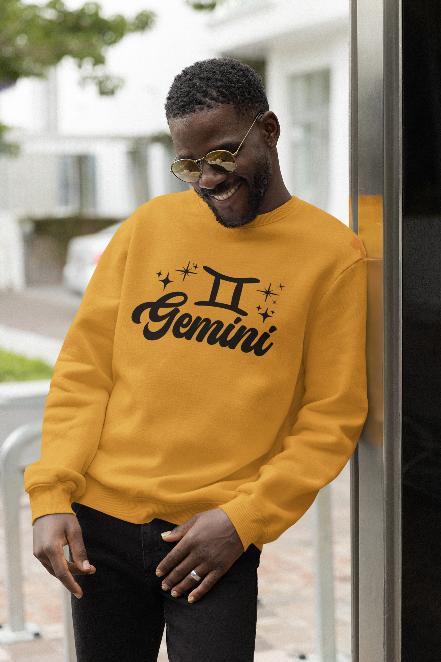 Person wearing a gold 'Gemini' black text design sweatshirt with zodiac symbol outdoors.