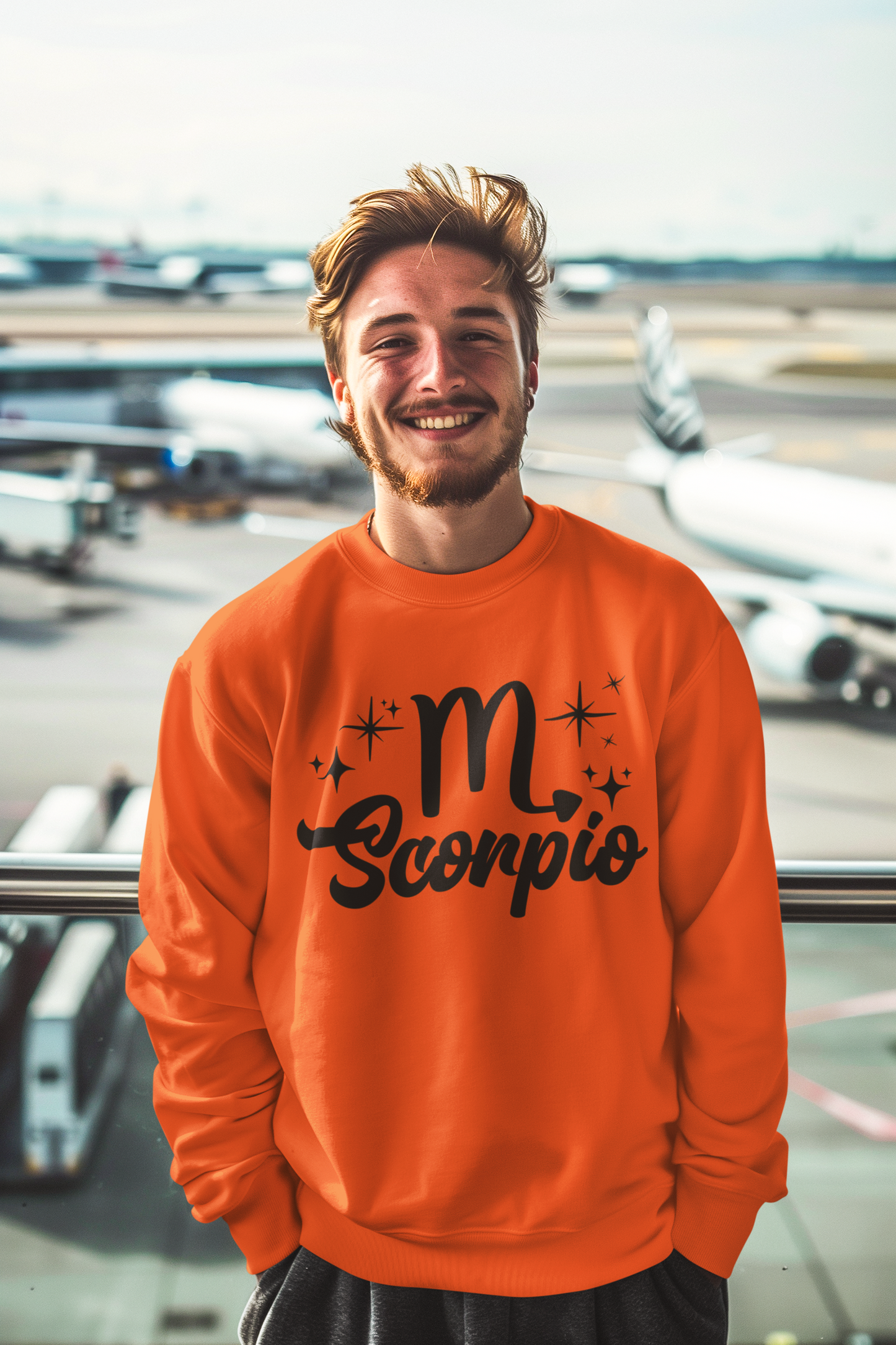 Man wearing a orange sweatshirt with 'Scorpio' black text design at an airport.