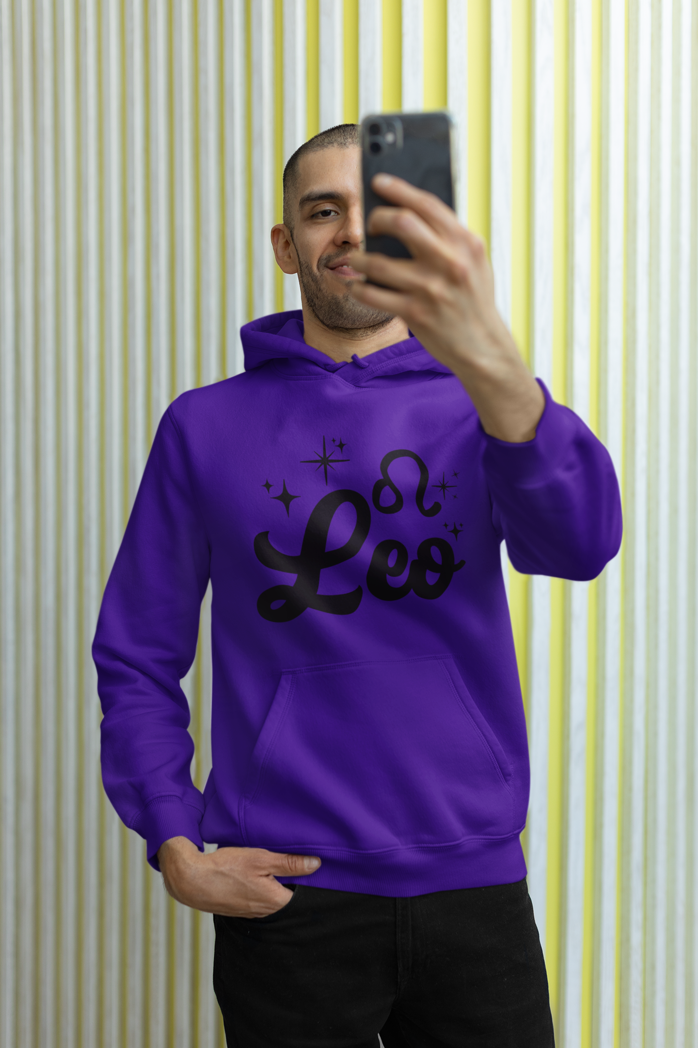 Person wearing a purple hoodie with 'Leo' black text, taking a selfie against a striped wall.
