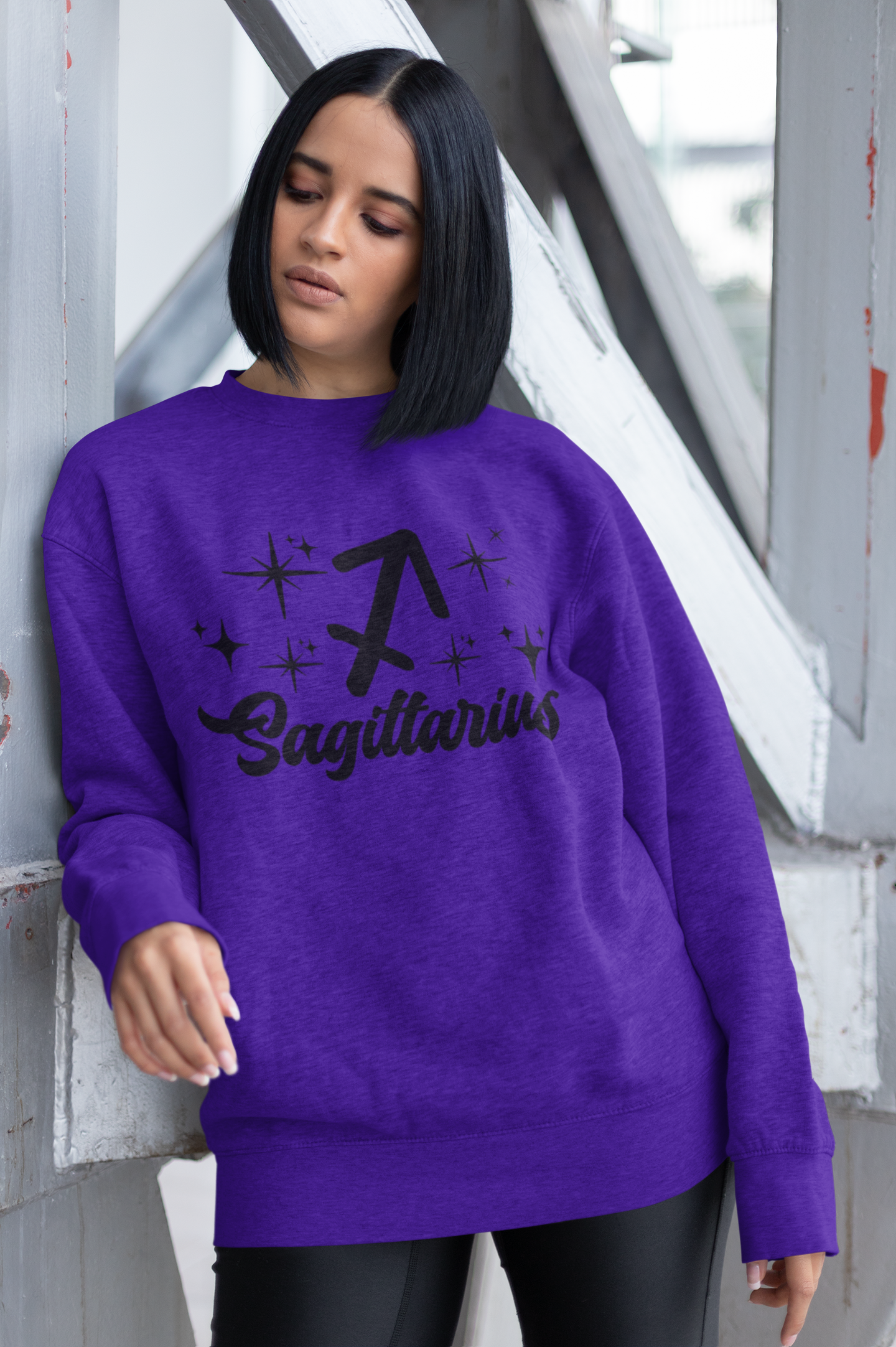 Person wearing a purple sweatshirt with 'Sagittarius' black text design outdoors.