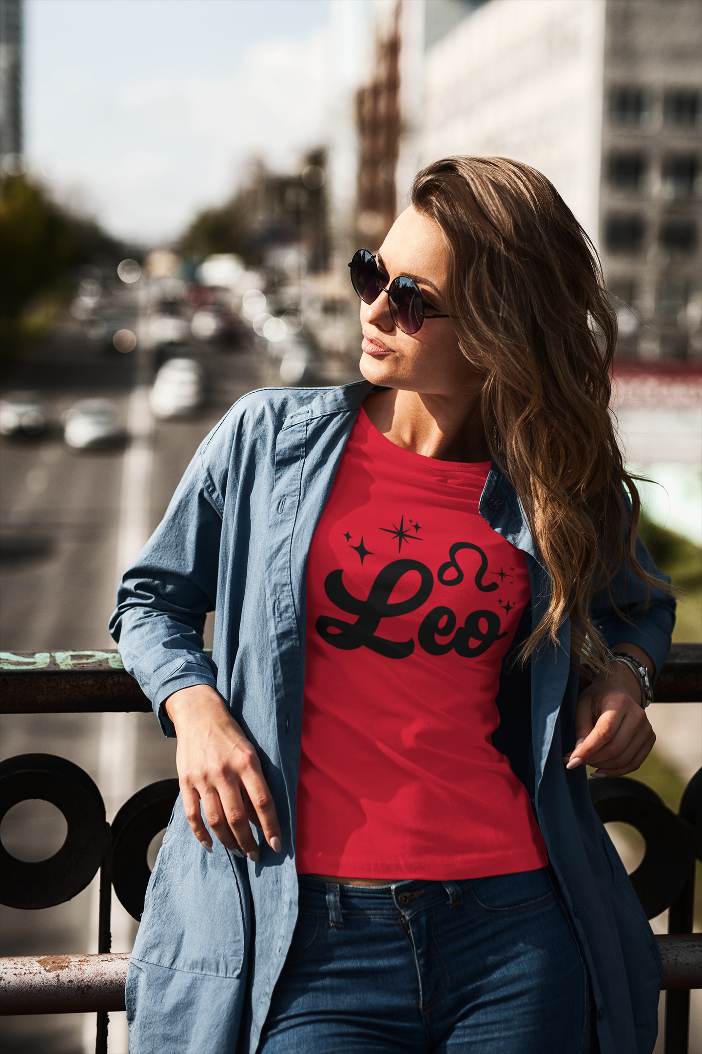Woman wearing a red t-shirt with 'Leo' black text design standing on a overpass.