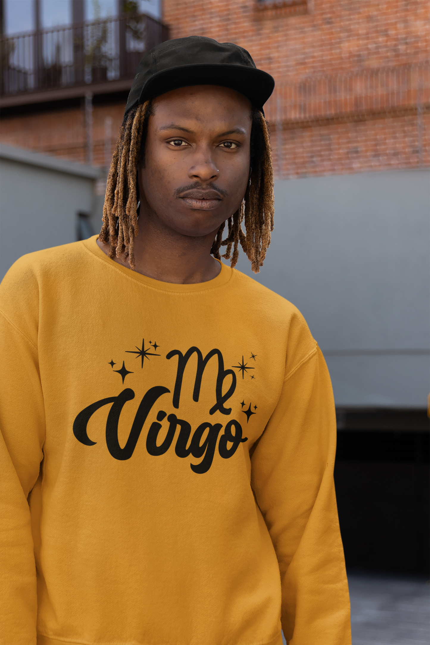 Person wearing an gold sweatshirt with 'Virgo' black text design, standing outdoors.