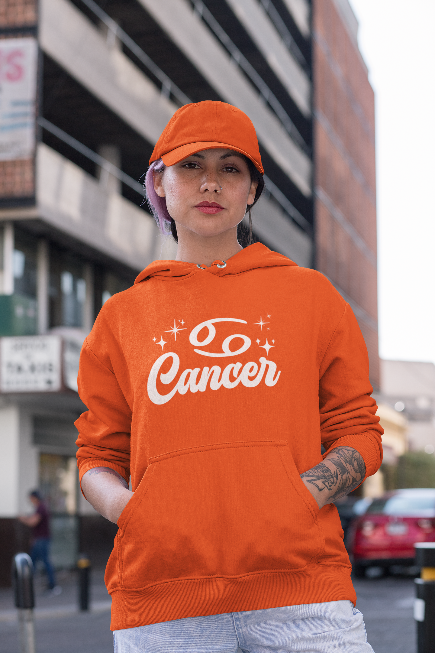 Person wearing a orange hoodie with 'Cancer' white text in an urban setting
