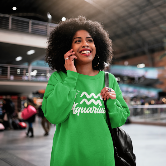 Woman in a green 'Aquarius' white text design sweatshirt talking on a phone in an indoor setting