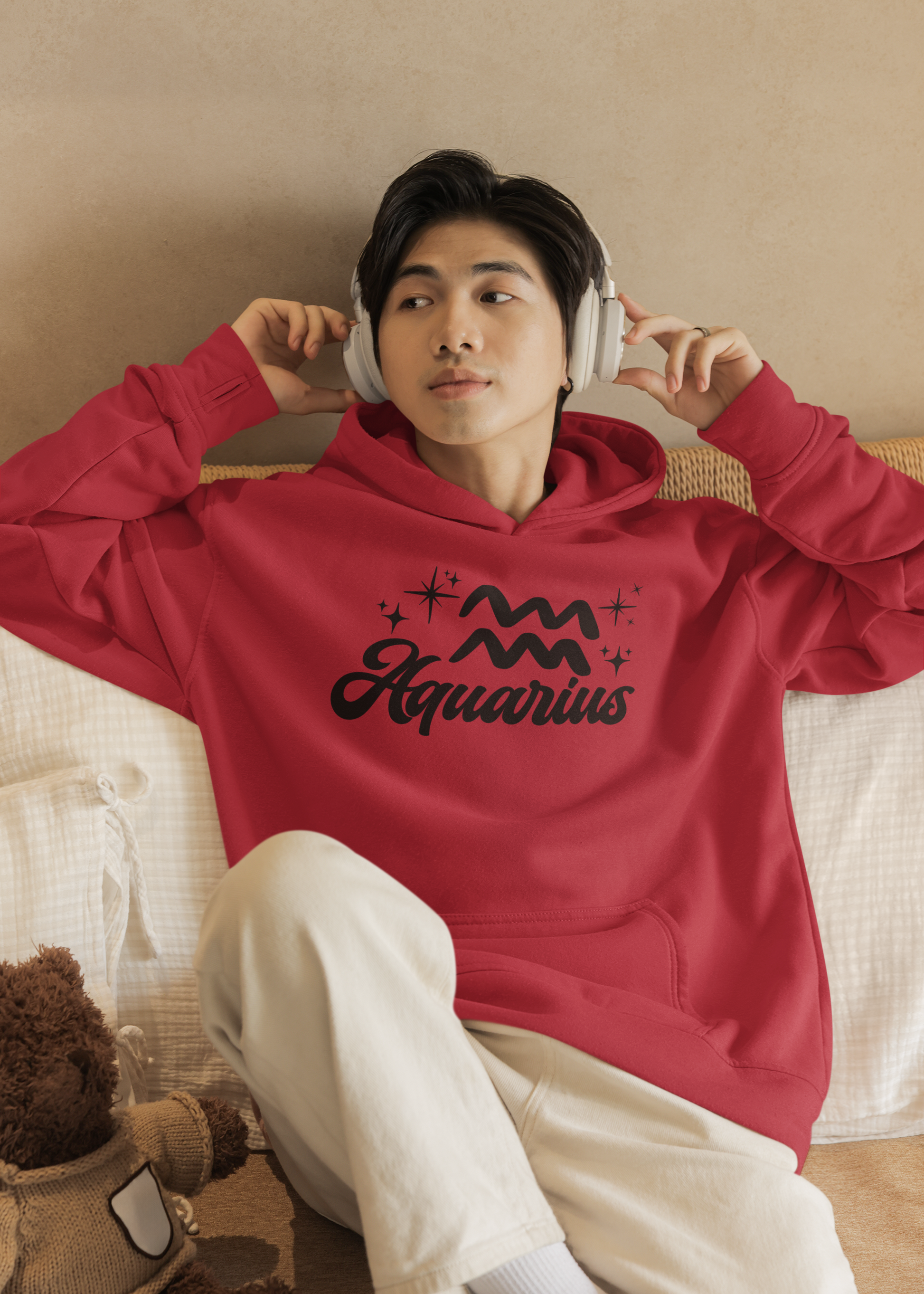 Person wearing a red hoodie with 'Aquarius' black text with zodiac symbol, sitting on a couch.