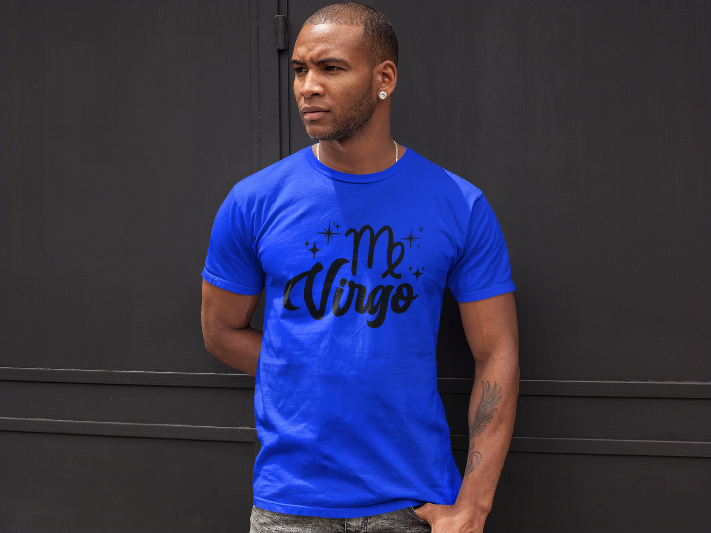 Man wearing a blue t-shirt with 'Virgo' black text against a black wall background