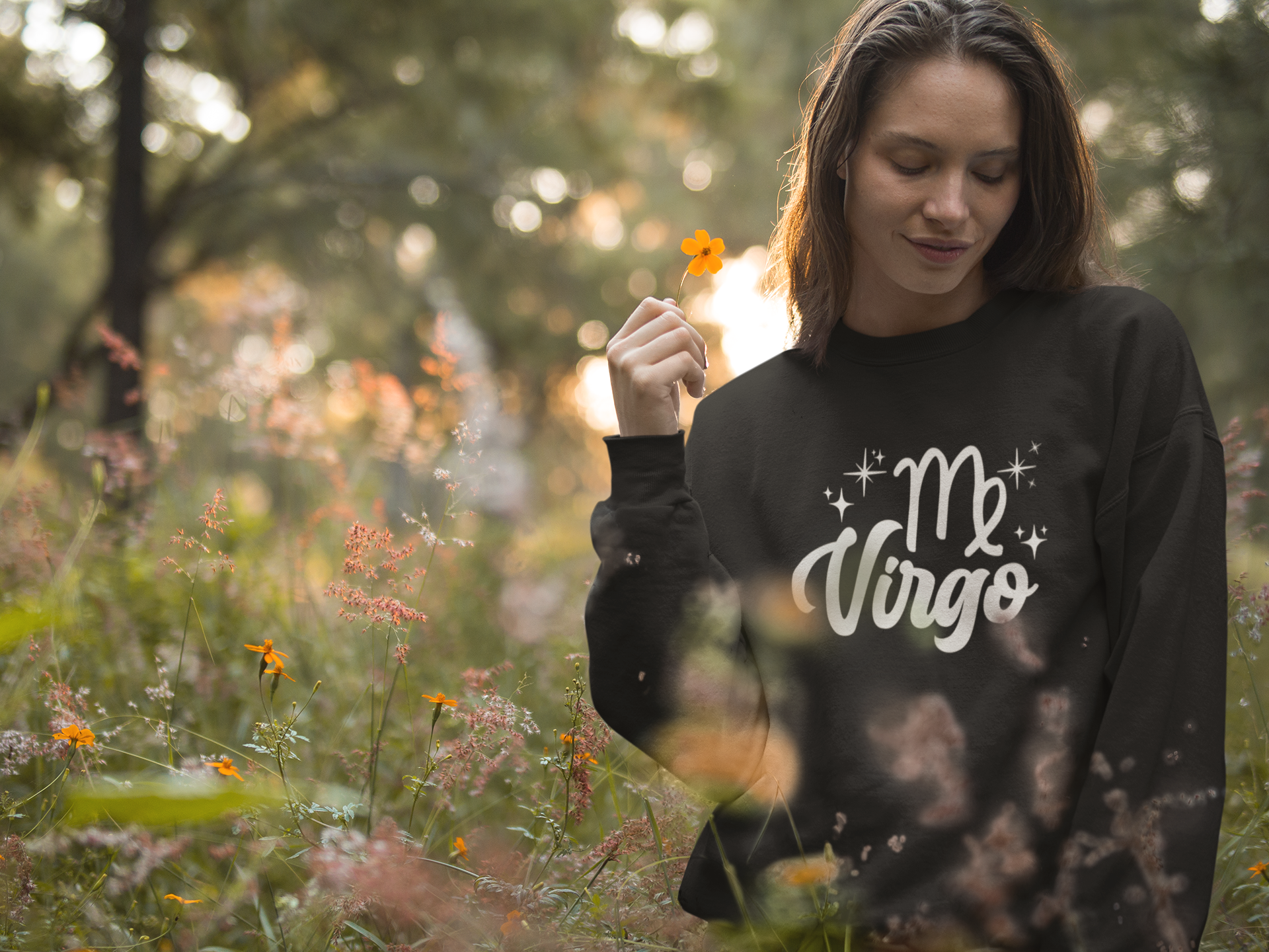 Woman wearing a black 'Virgo' white text design sweatshirt in a field of flowers