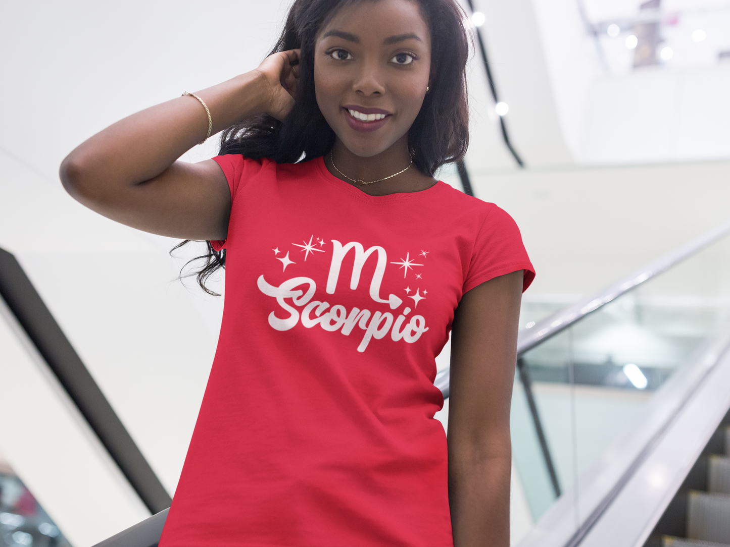 Woman wearing a red t-shirt with 'Scorpio' white text design, standing on escalator.
