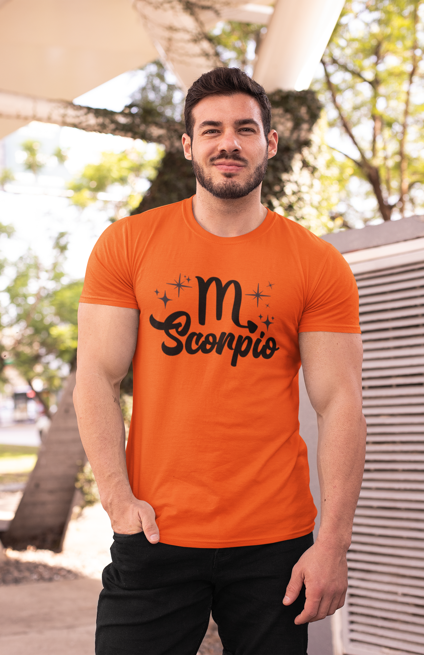 Man wearing an orange t-shirt with 'Scorpio' black text design outdoors.