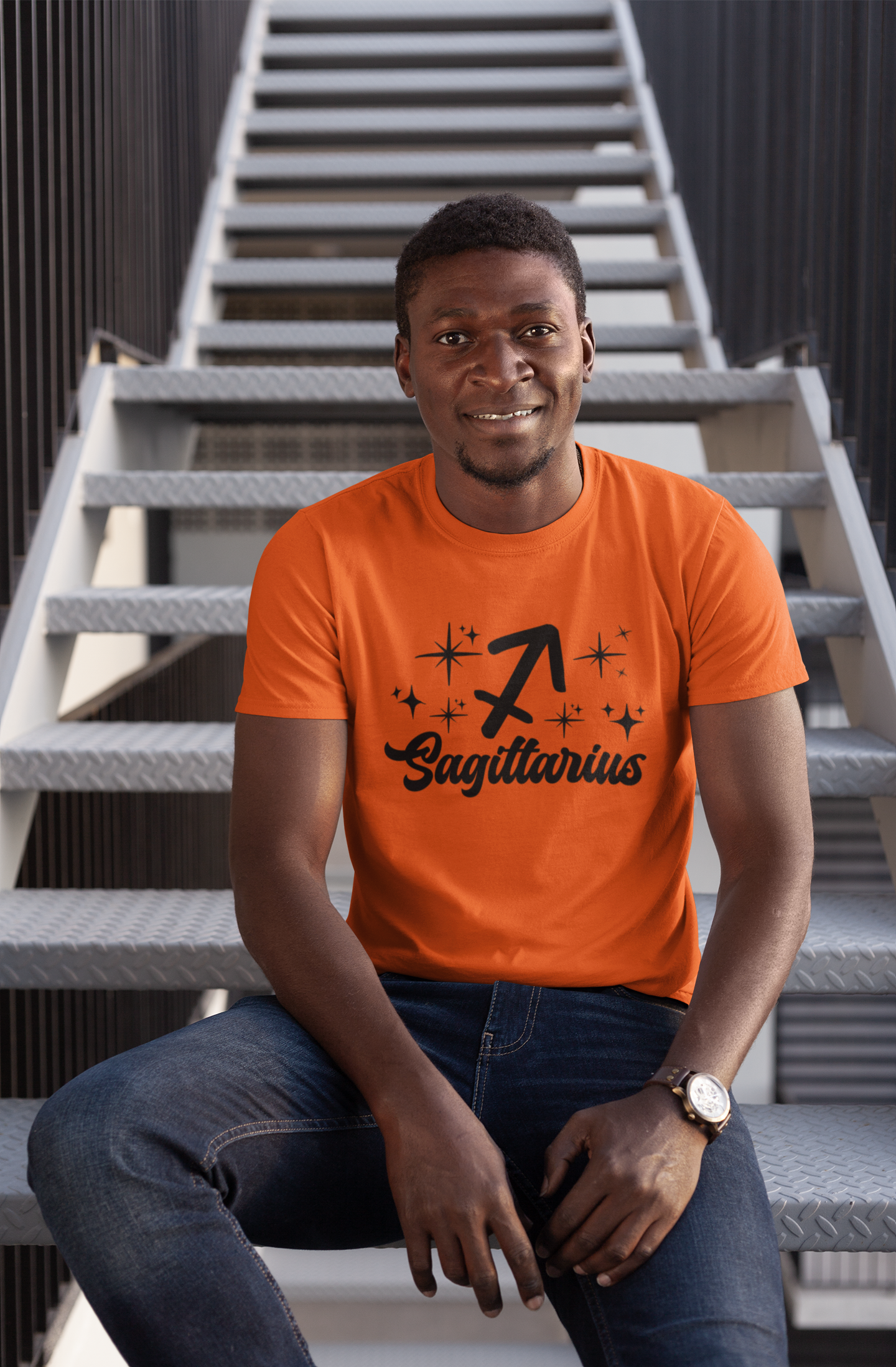 Man wearing a orange t-shirt with 'Sagittarius' black text design sitting on stairs.