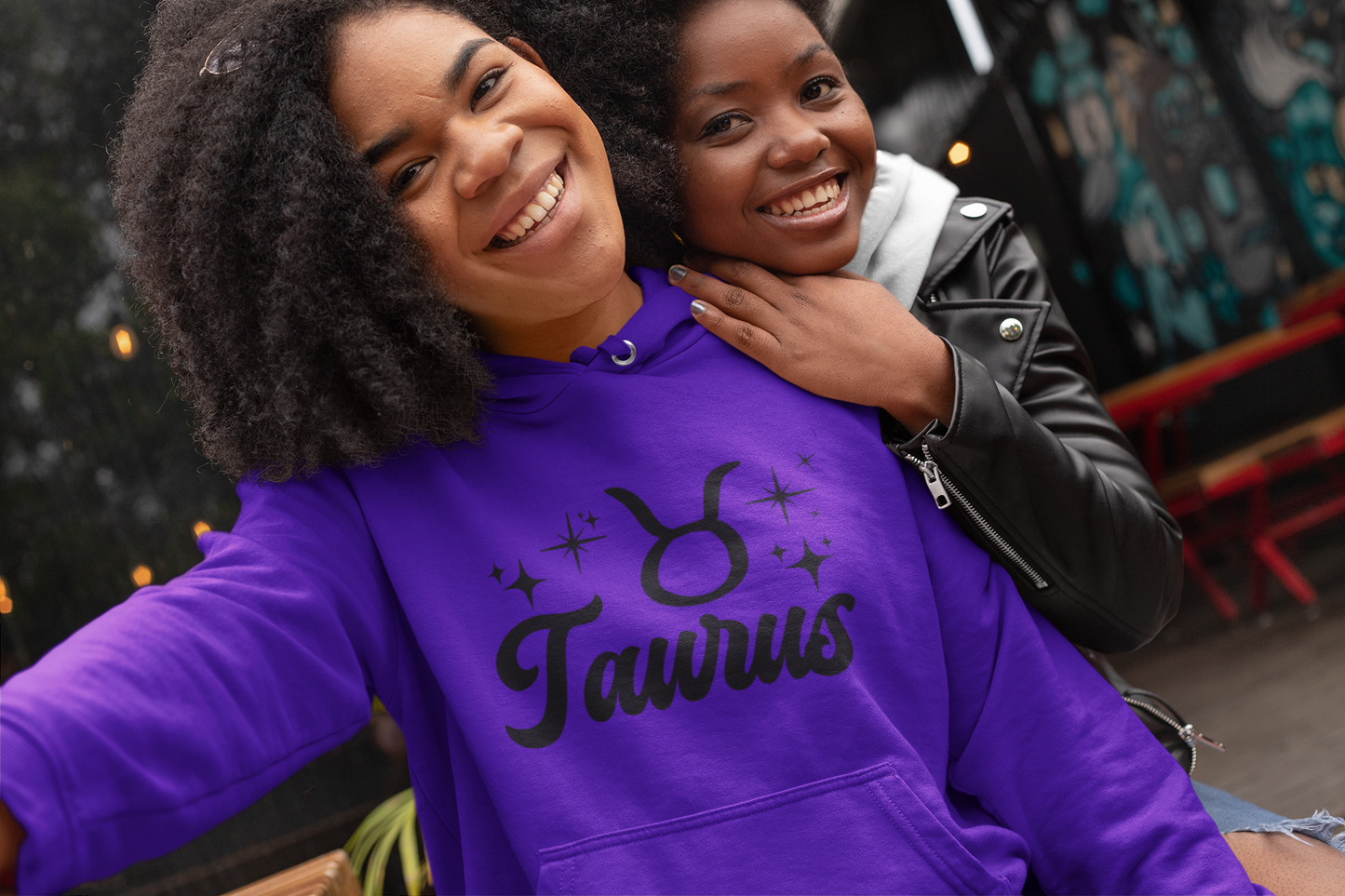 Two people posing together, one wearing a purple 'Taurus' hoodie, black text design 