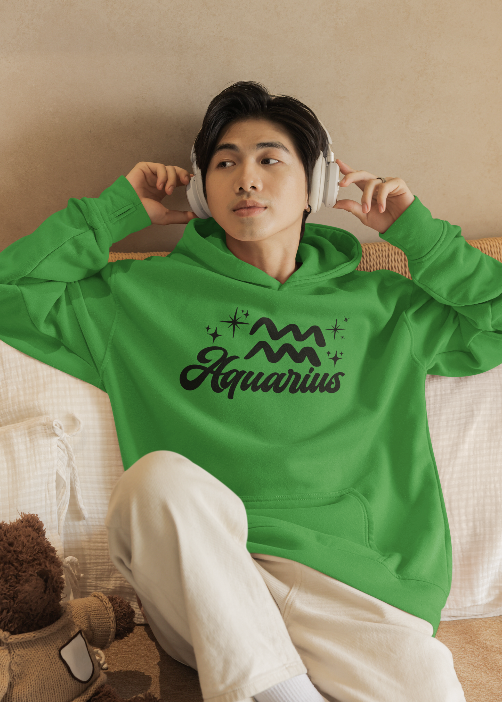 Person wearing a green hoodie with 'Aquarius' black text with zodiac symbol, sitting on a couch.
