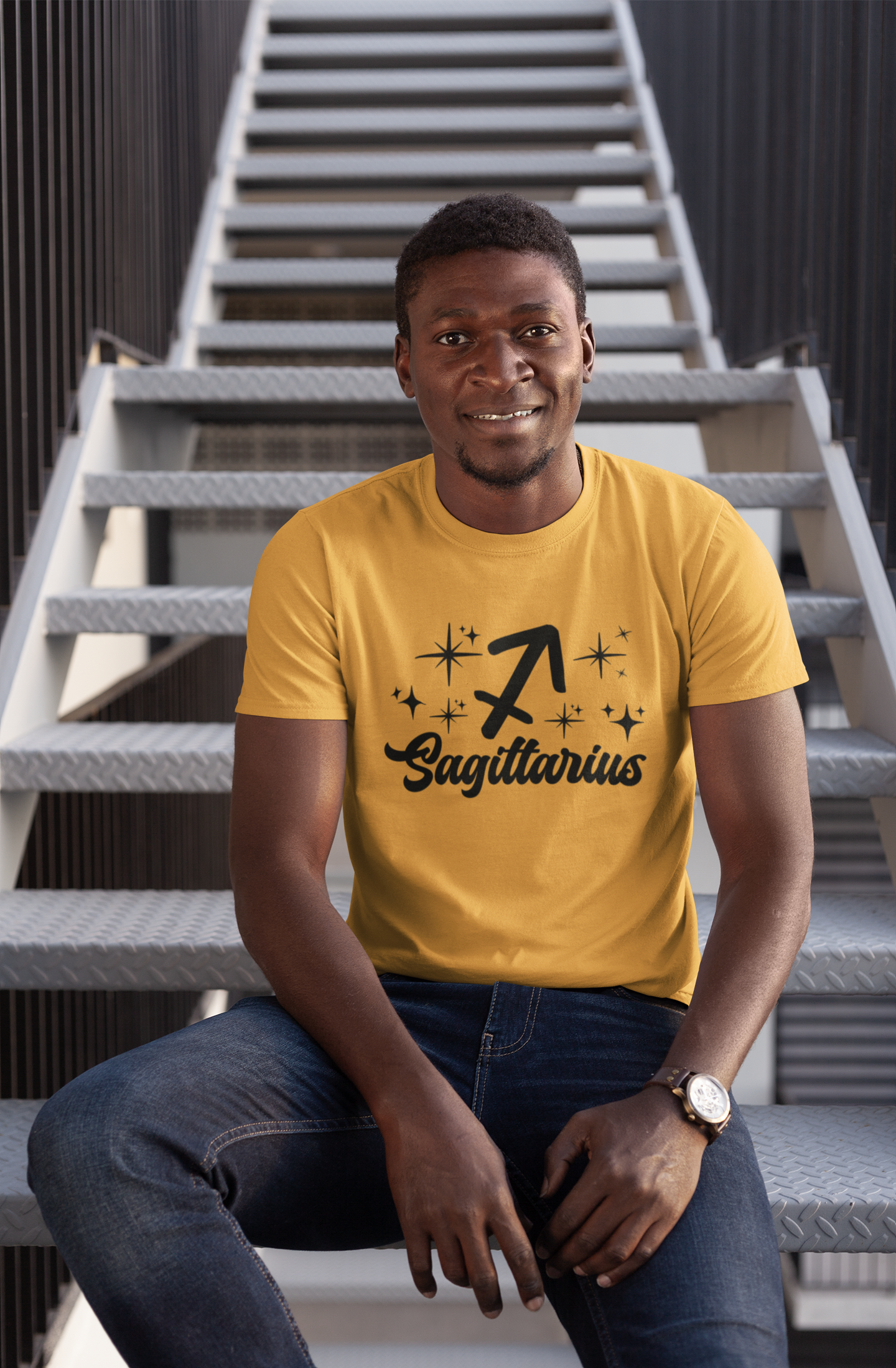 Man wearing a gold t-shirt with 'Sagittarius' black text design sitting on stairs.