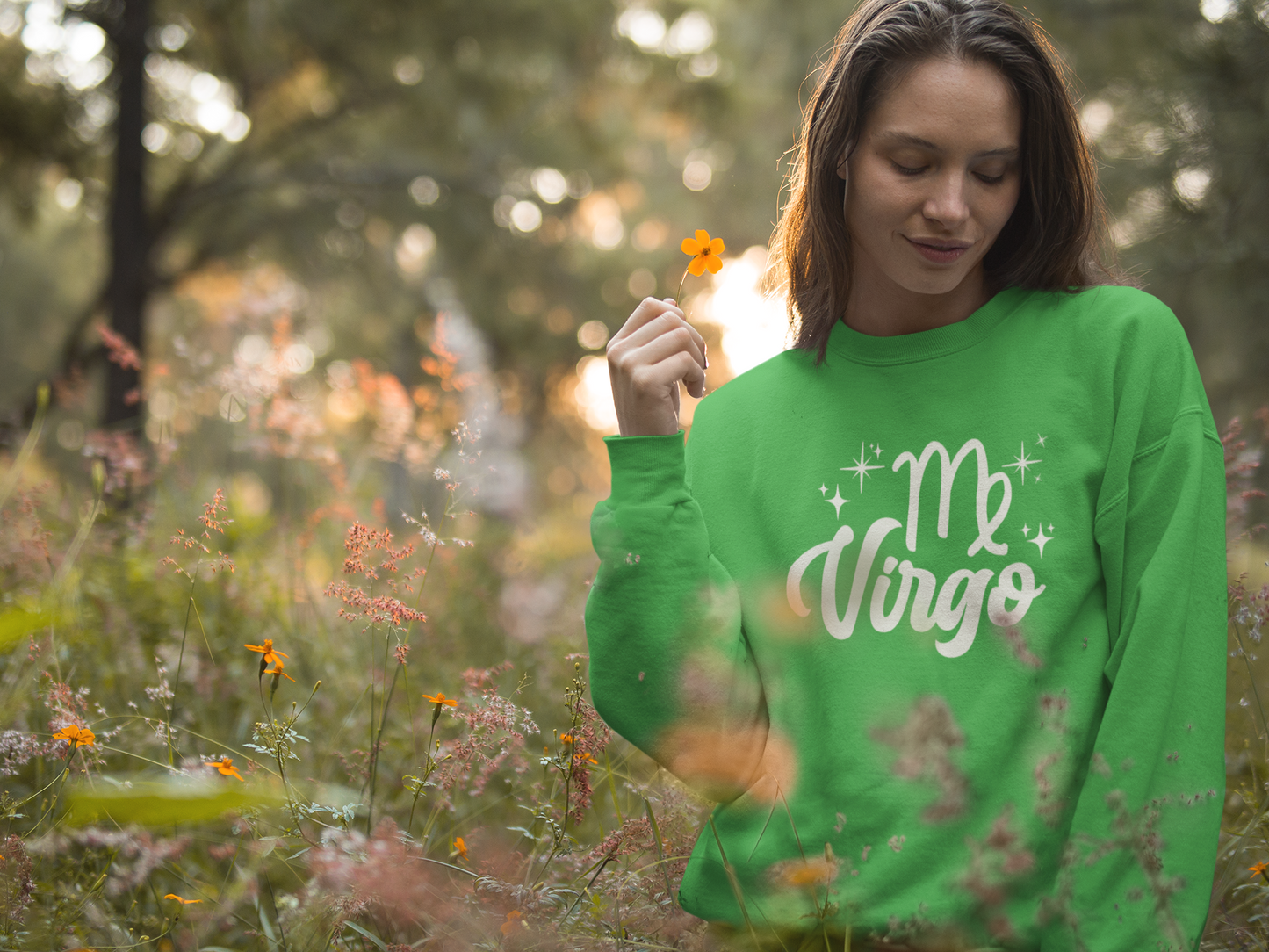 Woman wearing a green 'Virgo' white text design sweatshirt in a field of flowers