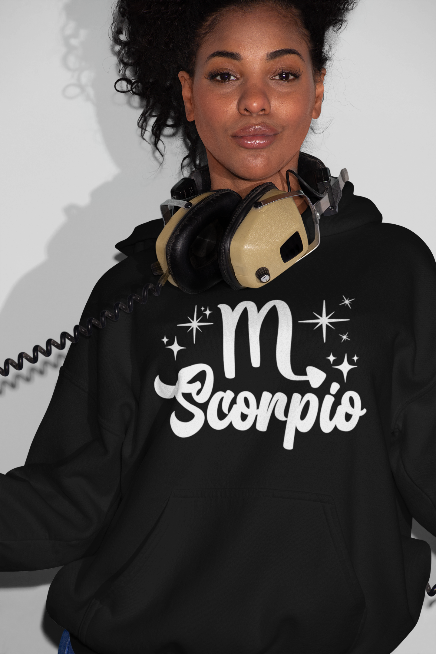 Person wearing a black hoodie with 'Scorpio' white text design, with headphones