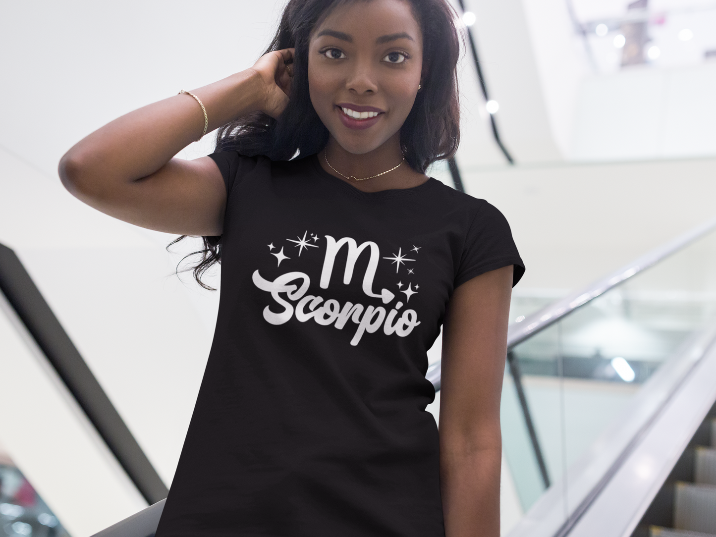 Woman wearing a black t-shirt with 'Scorpio' white text design, standing on escalator.