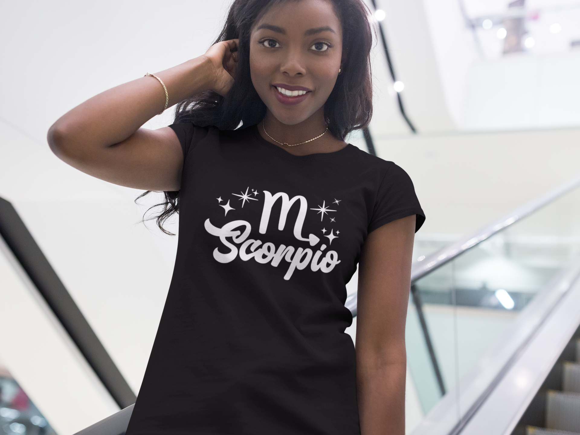 Woman wearing a black t-shirt with 'Scorpio' white text design, standing on escalator.
