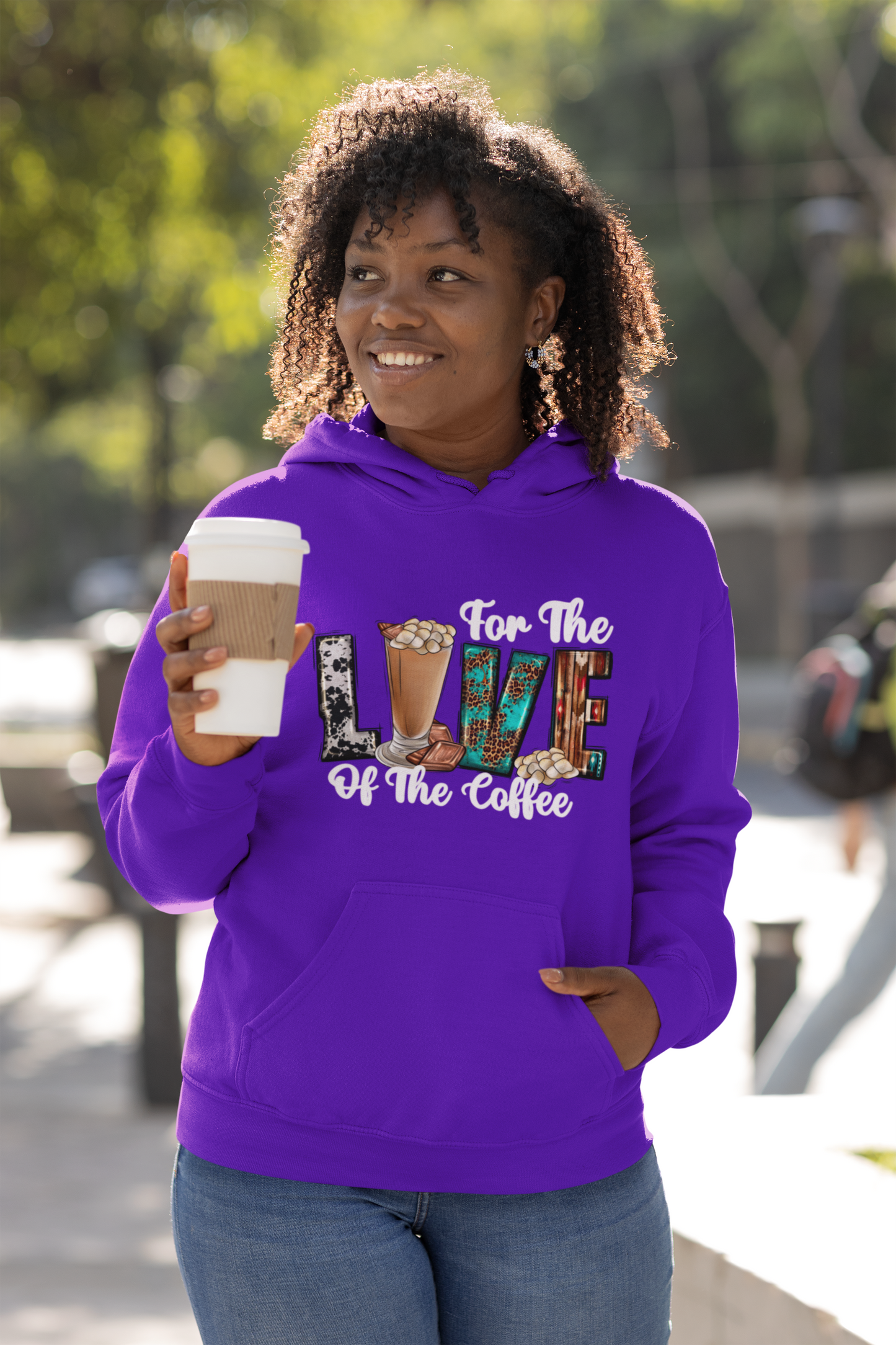 Coffee enthusiast wearing a purple hoodie with 'For the Love of Coffee' text, holding a coffee cup outdoors.