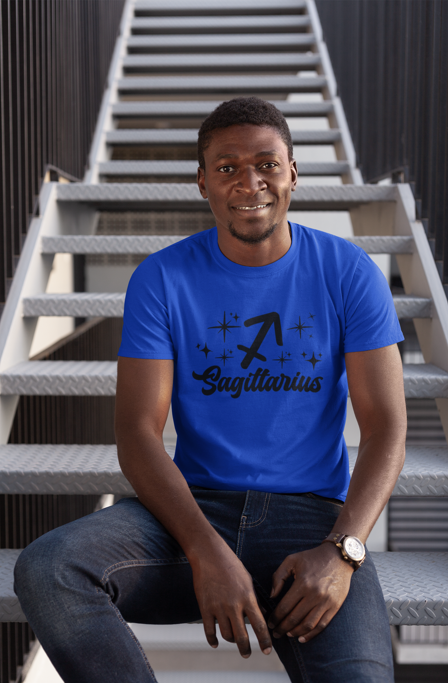 Man wearing a blue t-shirt with 'Sagittarius' black text design sitting on stairs.