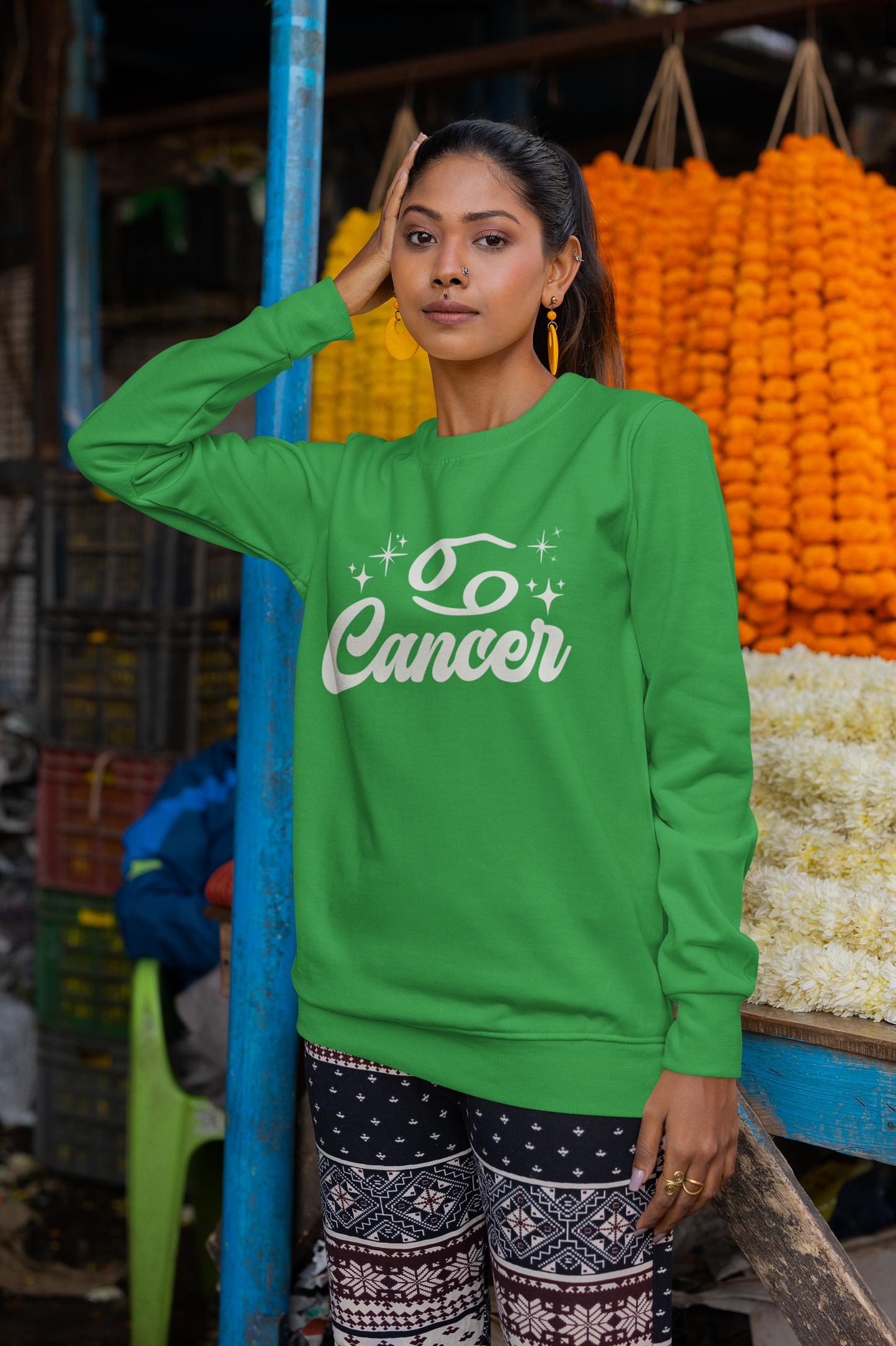 Woman wearing a green sweatshirt with 'Cancer' white text in an outdoor market setting