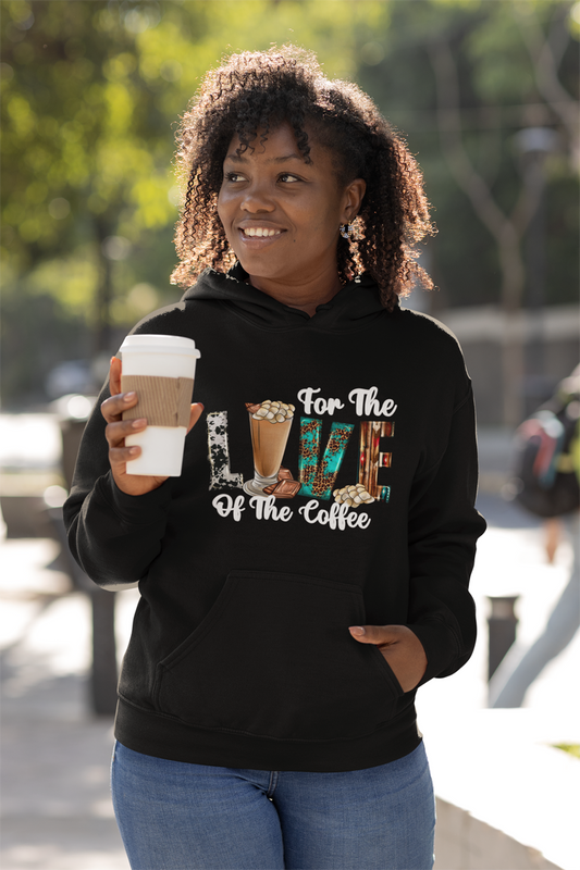 Coffee lover wearing a black hoodie with coffee-themed design, holding a coffee cup outdoors.