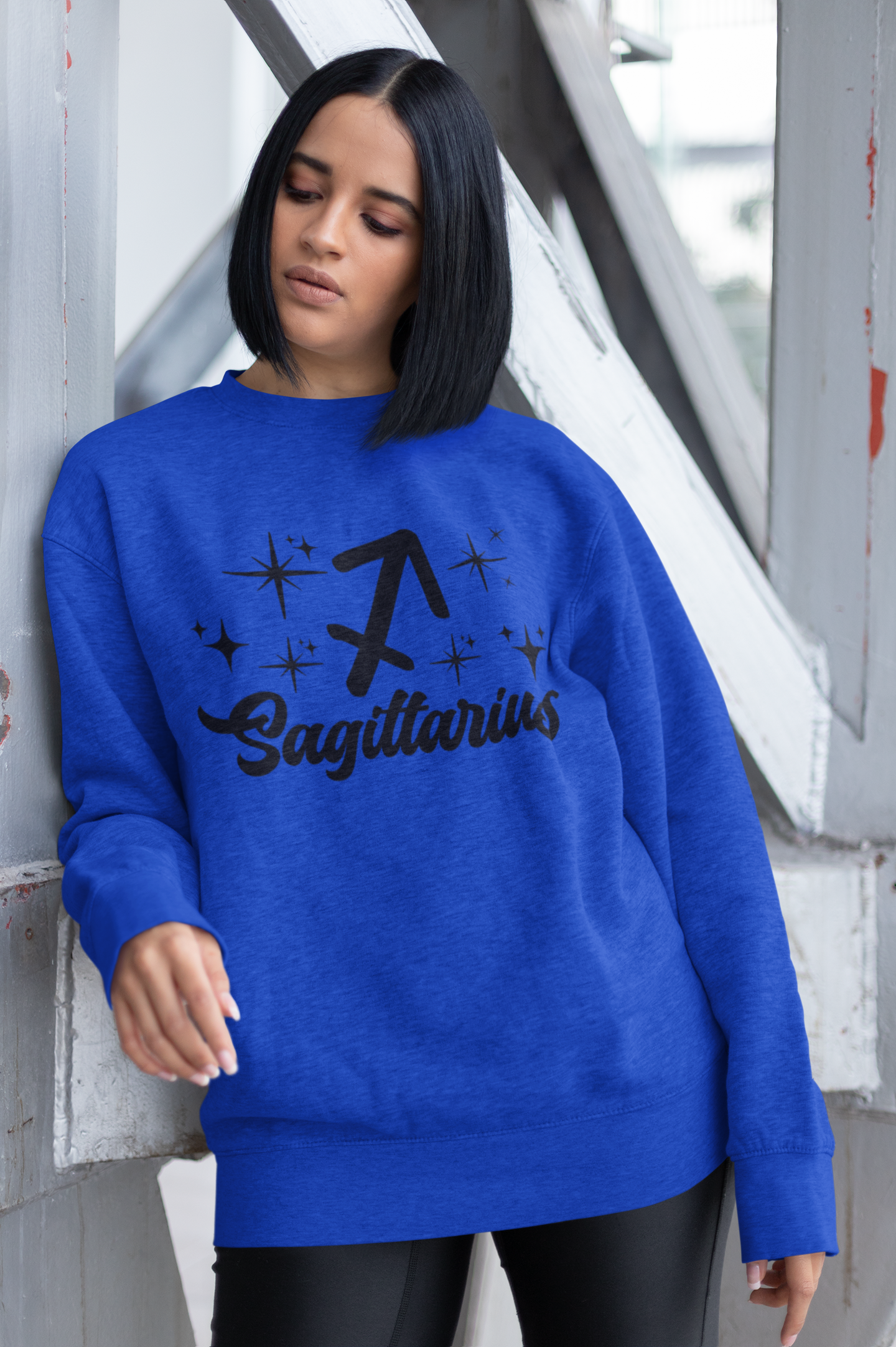 Person wearing a blue sweatshirt with 'Sagittarius' black text design outdoors.