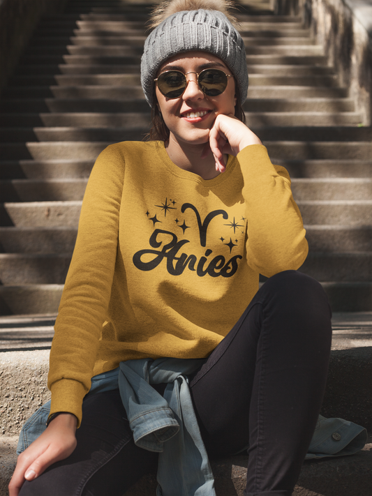 Person wearing a gold 'Aries' black text design sweatshirt sitting on steps.