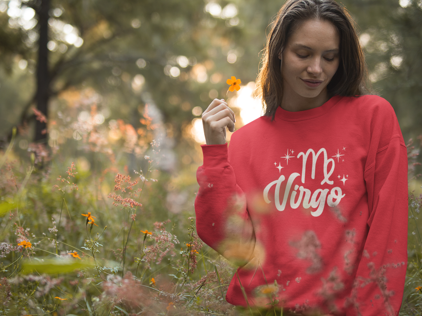 Woman wearing a red 'Virgo' white text design sweatshirt in a field of flowers